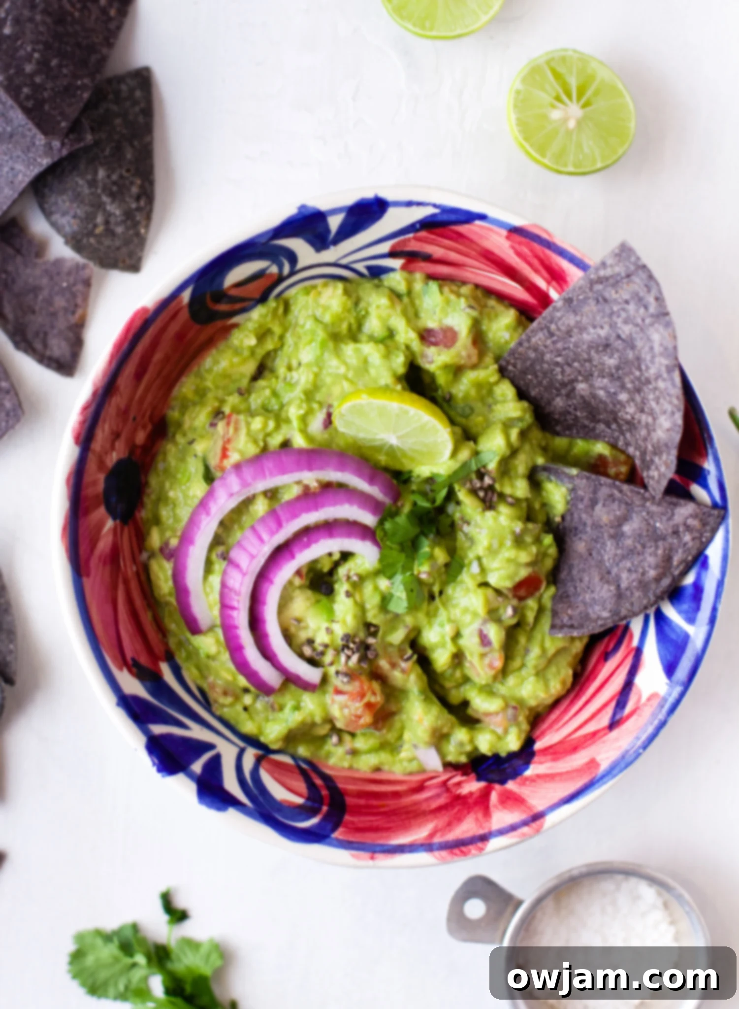 Easy Guacamole Recipe in a vibrant purple bowl, served with tortilla chips. This fresh, homemade avocado dip is perfect for appetizers or as a side with Mexican dishes.