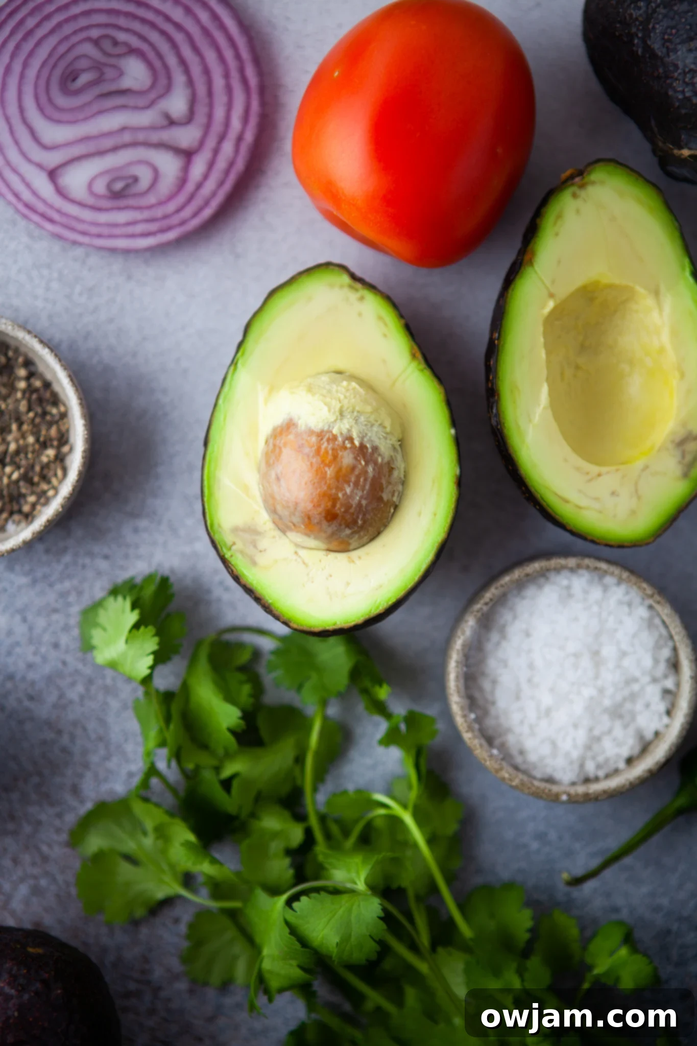 Fresh ingredients for Easy Guacamole Recipe laid out, including ripe avocados, red onion, cilantro, lime, and jalapeño.