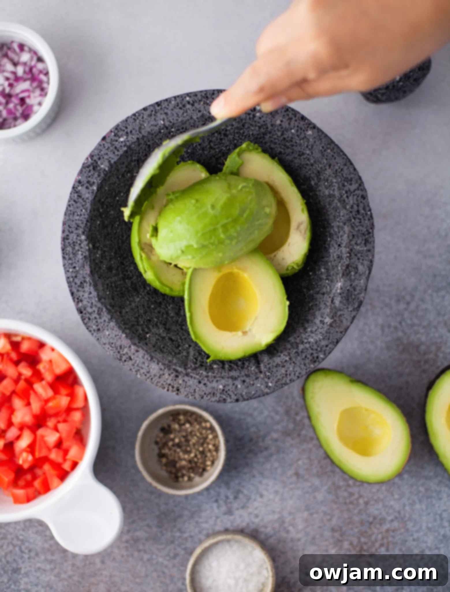 Mashing ripe avocados with a spoon in a molcajete for an Easy Guacamole Recipe.