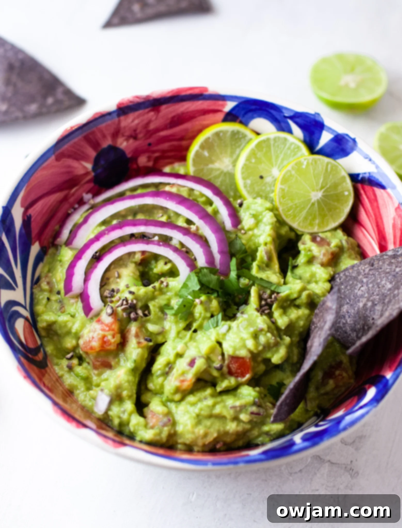 Easy Guacamole Recipe being mixed with finely minced red onion, showing the fresh ingredients combining.