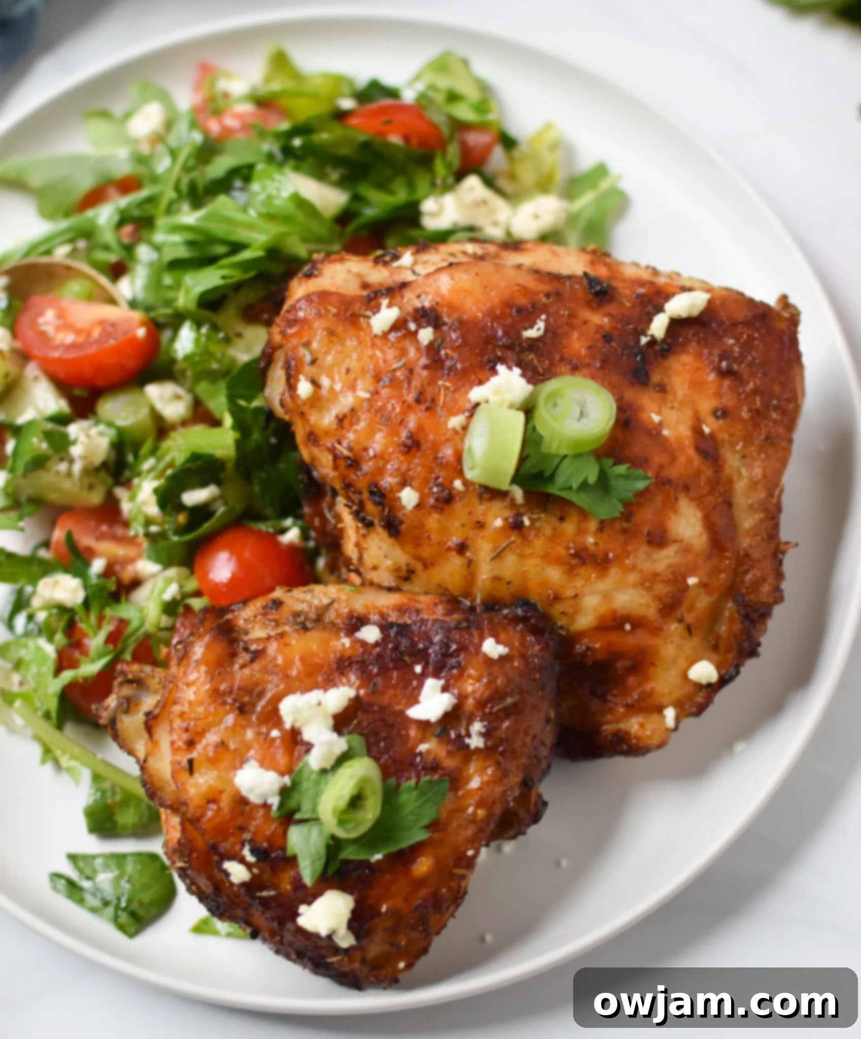 Air Fryer Mediterranean Chicken Thighs on a white plate, garnished with fresh herbs.