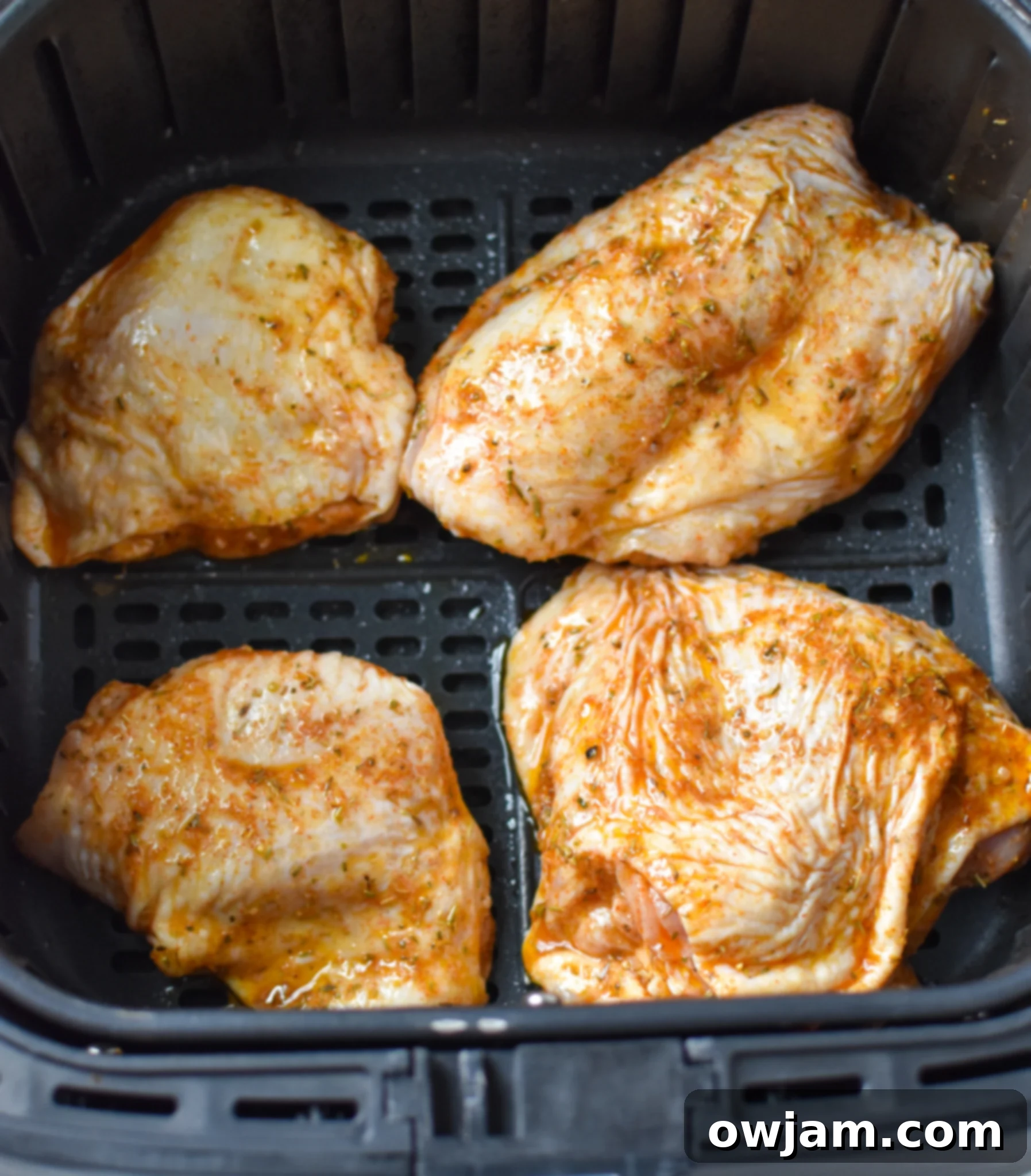 Air Fryer Mediterranean Chicken Thighs cooking in an air fryer.
