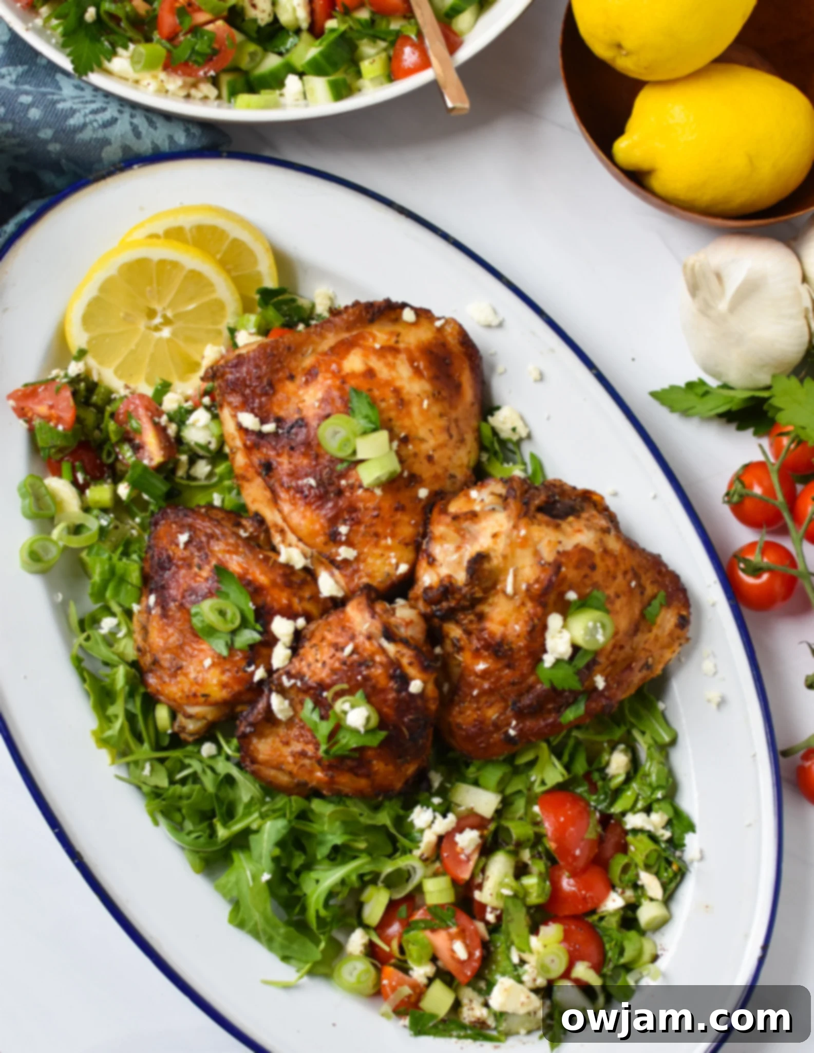 Air Fryer Mediterranean Chicken Thighs beautifully arranged on a white platter with herbs.