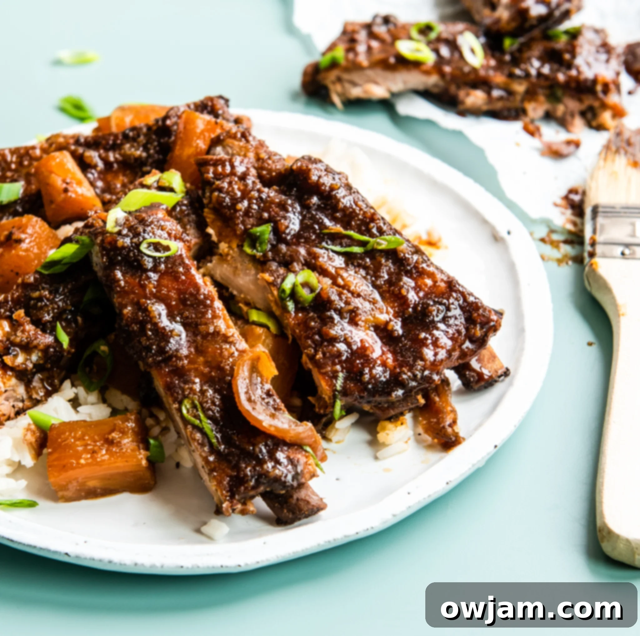 Aloha Slow Cooker Pork Ribs 2 Slow Cooker Hawaiian Pork Ribs on a plate, garnished with green onions and fresh pineapple.