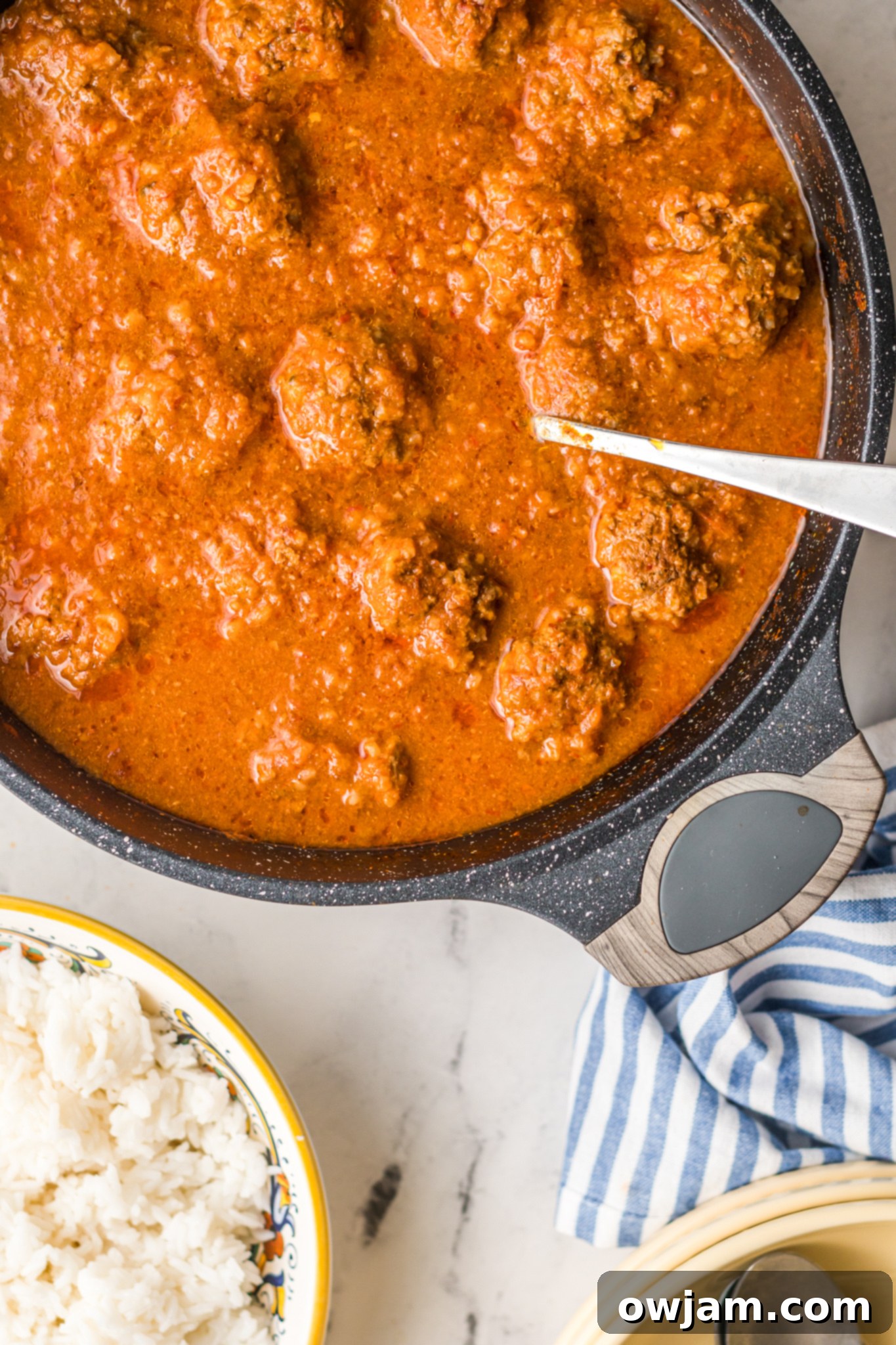 Chipotle Meatballs 4 Albondigas en Chipotle meatballs simmering in a rich, red adobo sauce in a large pot, garnished with fresh herbs and ready to be served.