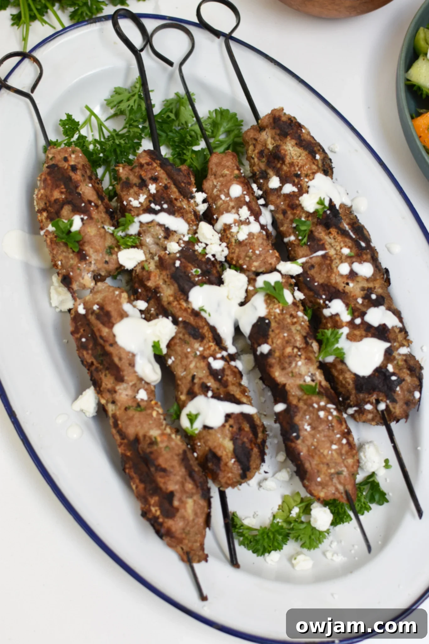 Savory Turkey Kofta Kebab 2 Turkey Kofta Kebab Recipe on a white platter, garnished with fresh herbs.