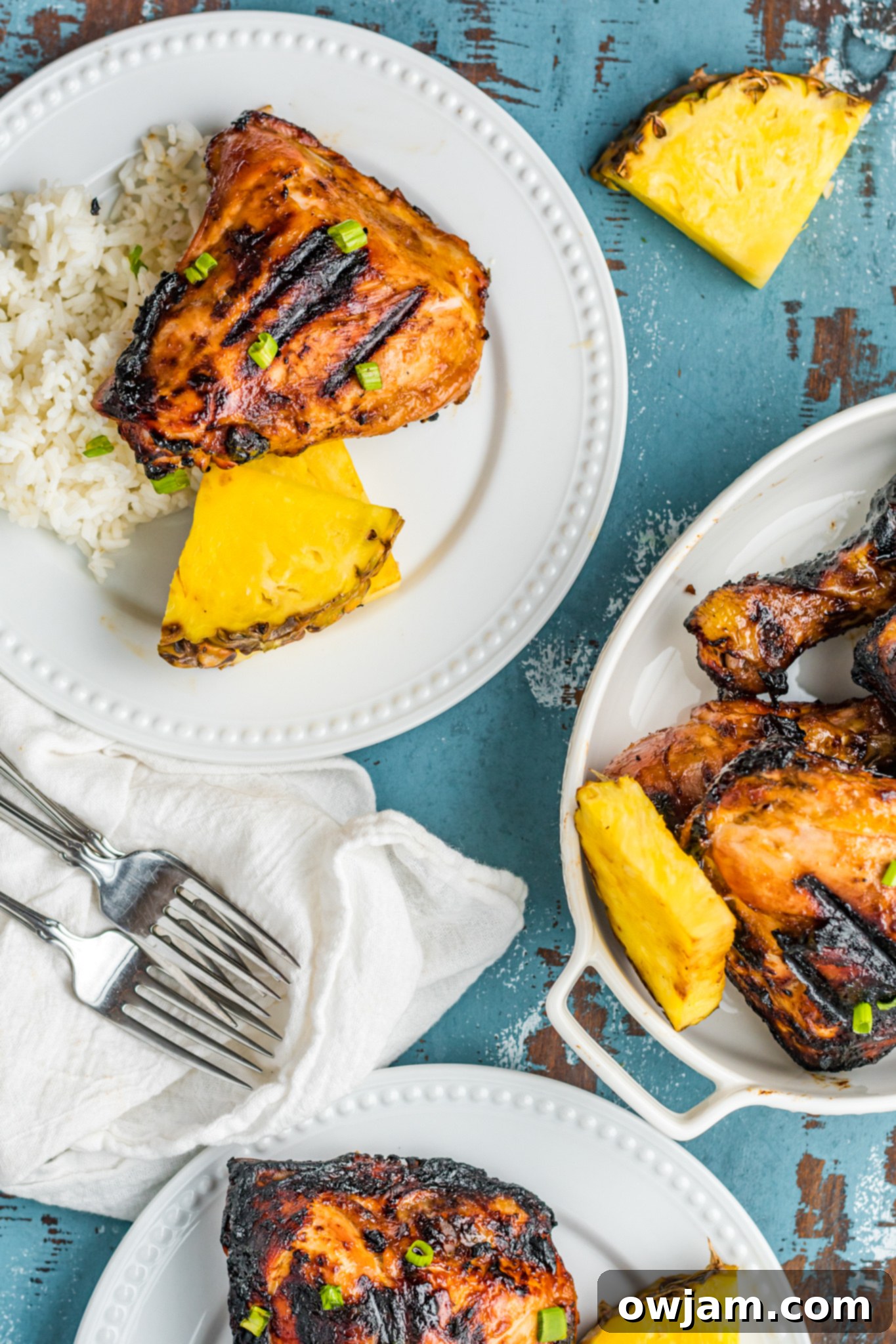 Hawaiian Fire Chicken 11 Two plates of Grilled Huli Huli Chicken, each with coconut rice and fresh pineapple, ready for serving.