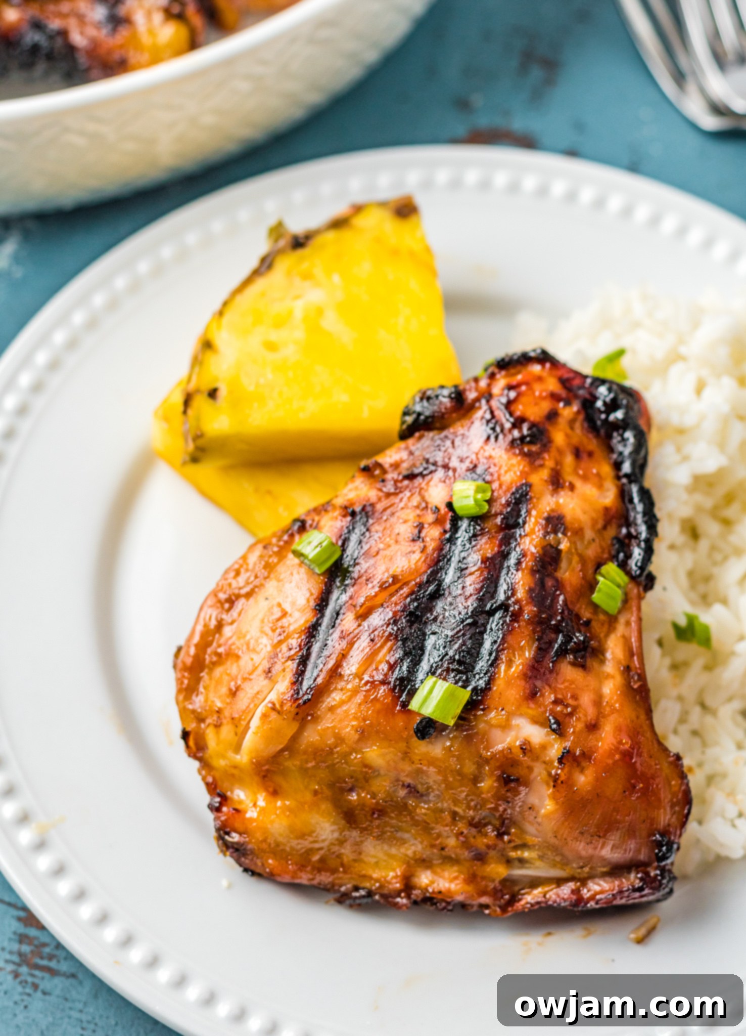 Hawaiian Fire Chicken 3 Grilled Huli Huli Chicken served on a plate with fresh pineapple slices and a hint of coconut rice.