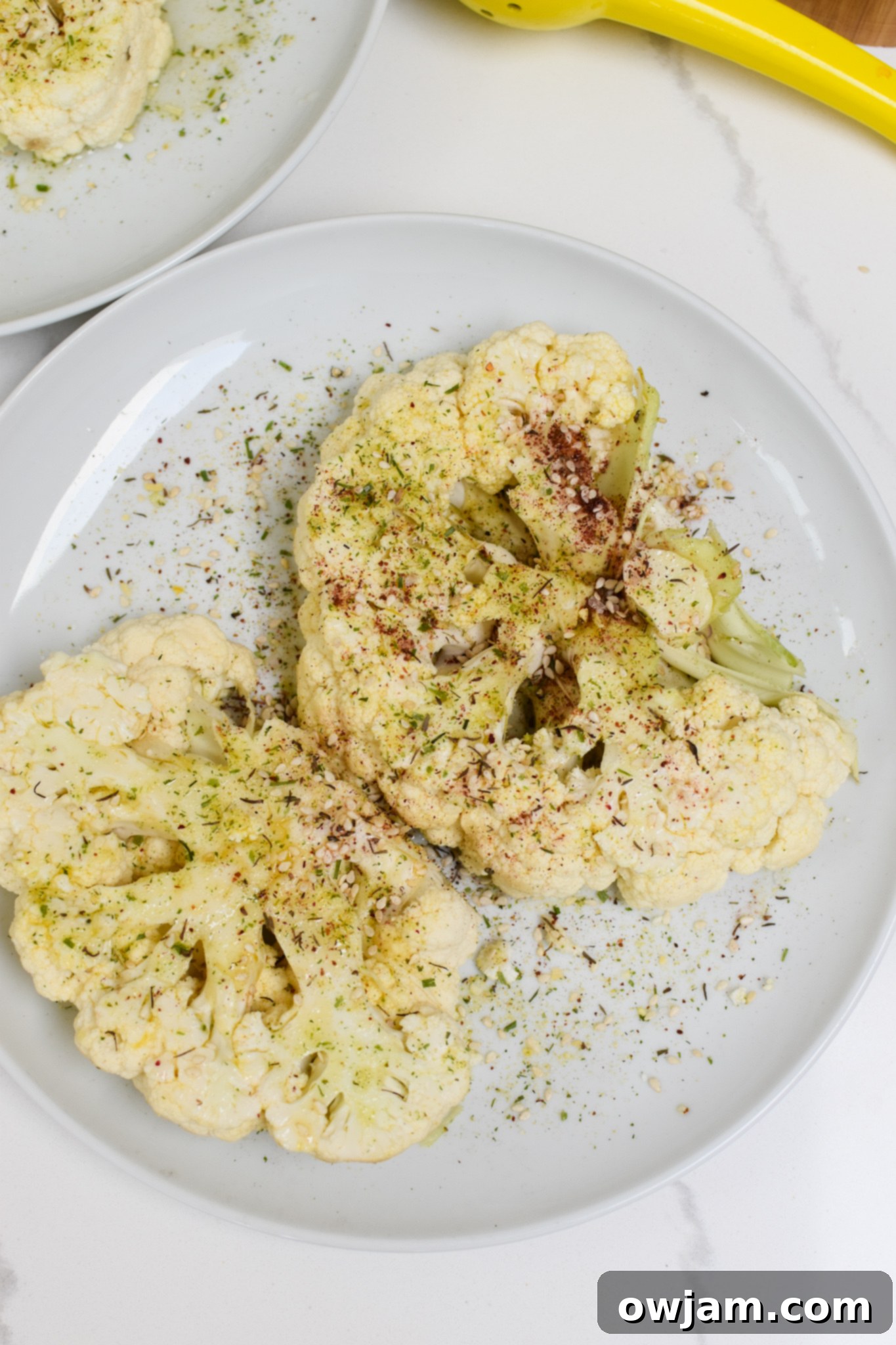 Cauliflower steaks seasoned with za'atar and olive oil on a white plate.