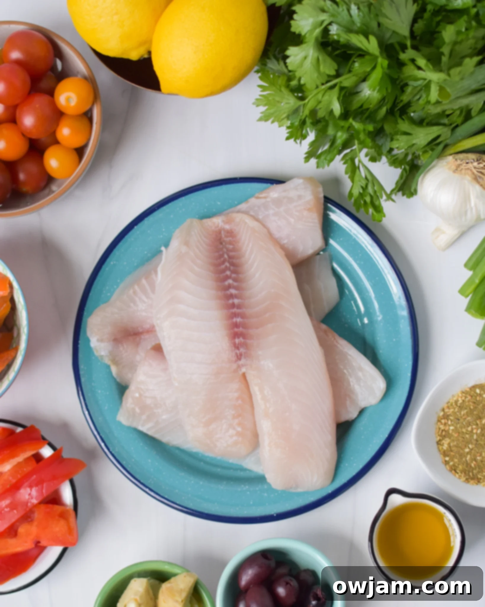 Golden Mediterranean Tilapia Bake 3 A selection of fresh ingredients for Mediterranean Baked Tilapia, including tilapia fillets, colorful vegetables, and a bowl of za'atar spice.
