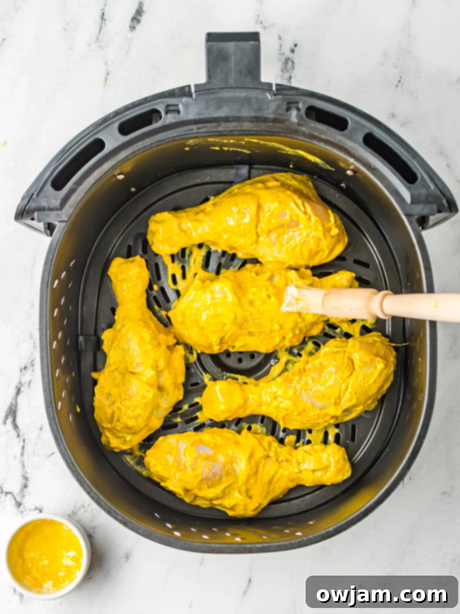 Air Fryer Tandoori Chicken Legs cooking in air fryer with marinade residue.
