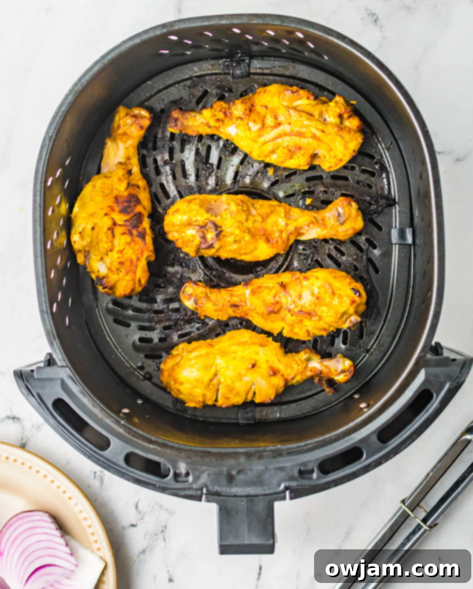 Air Fryer Tandoori Chicken Legs in air fryer basket, cooked.