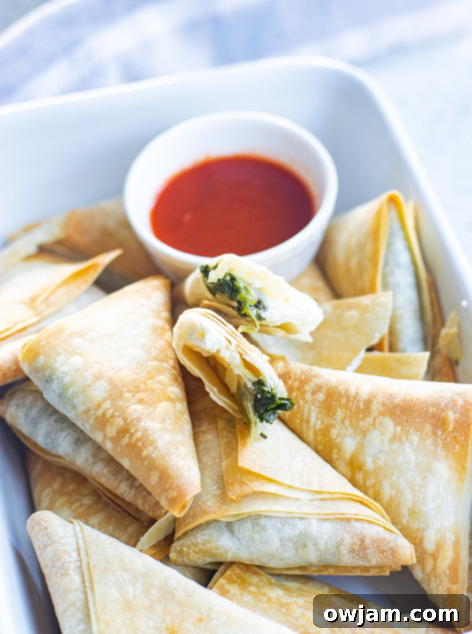 Crispy Spanakopita Pastries 3 Freshly baked Spanakopita Triangles Recipe in a white dish, ready to be served.