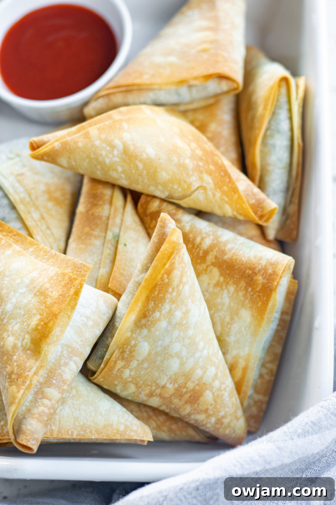 Crispy Spanakopita Pastries 4 Close-up of baked Spanakopita Triangles Recipe with a side of red dipping sauce.