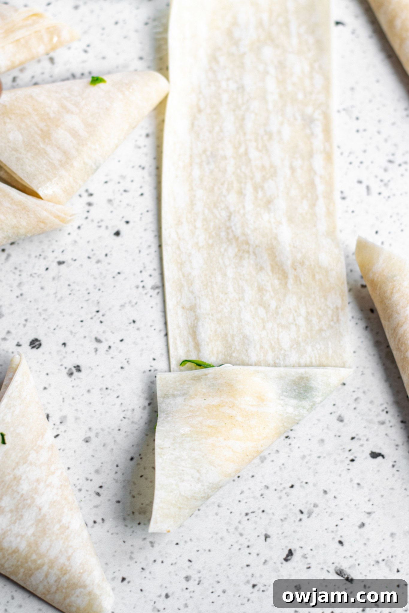 Crispy Spanakopita Pastries 7 Spanakopita Triangles Recipe phyllo dough being folded into a triangle shape.