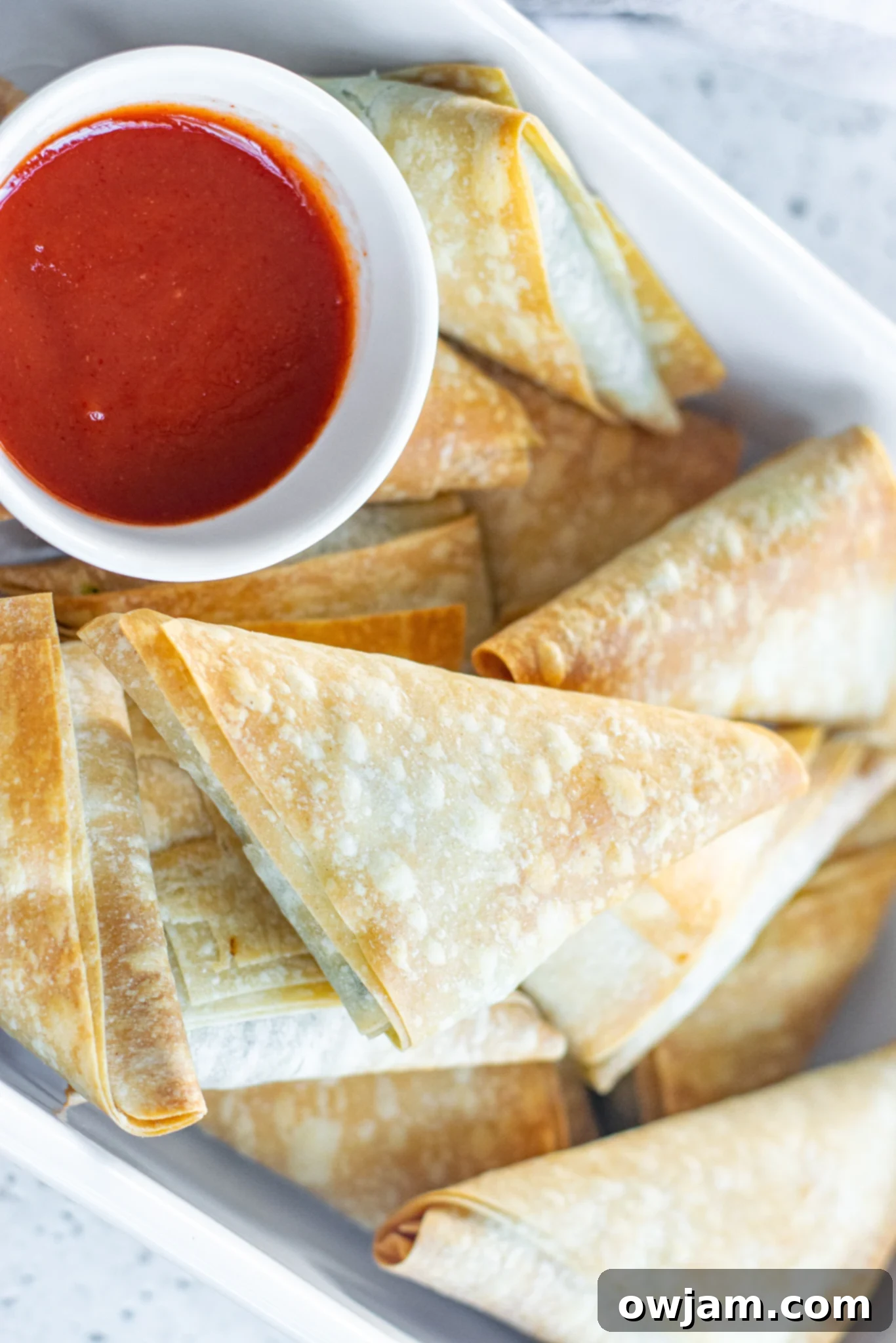 A large pan filled with golden-brown Spanakopita Triangles Recipe, fresh from the oven.