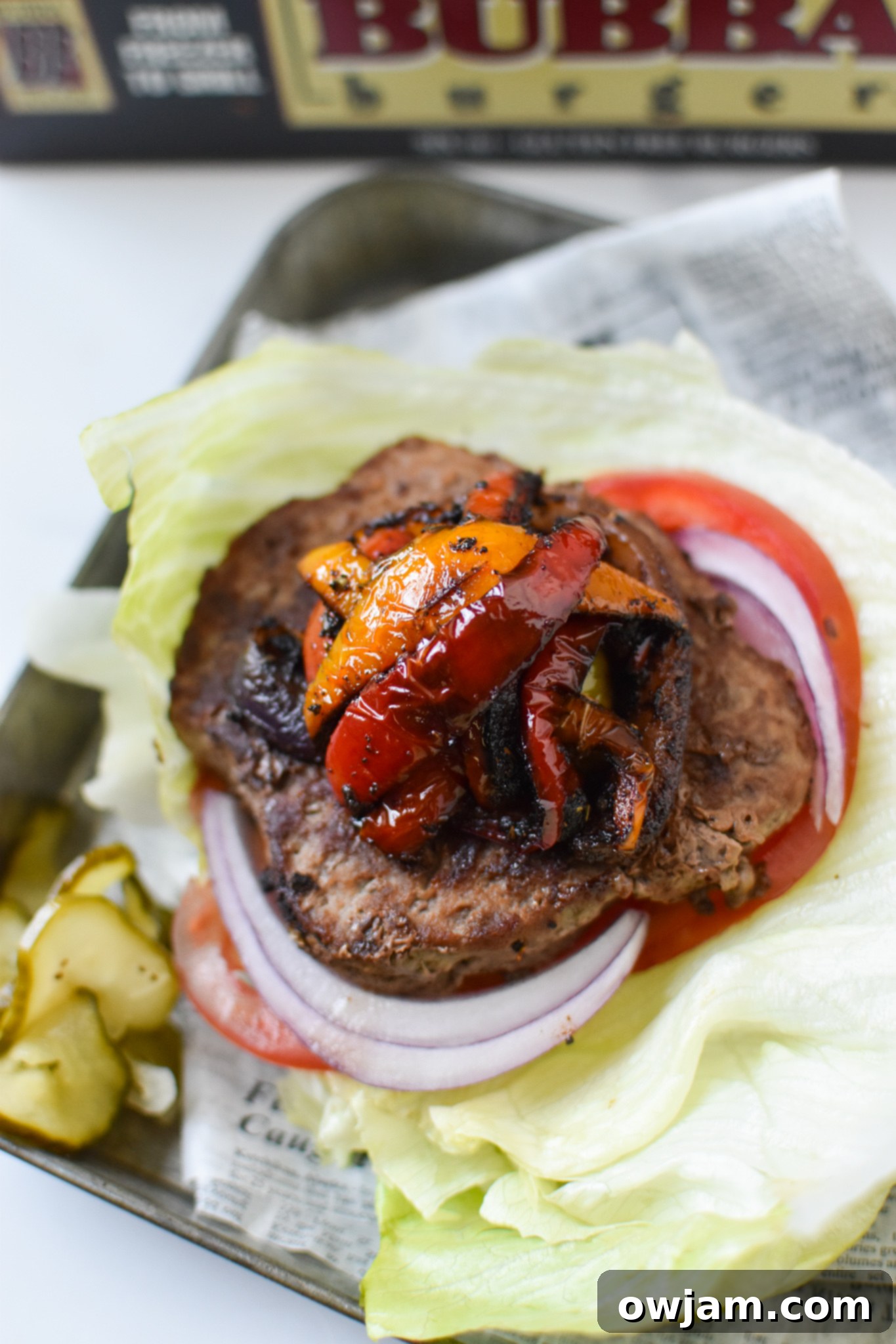 A delicious Fajita Lettuce Burger served on a metal plate, showcasing vibrant bell peppers and onions atop a juicy burger patty within a fresh lettuce wrap.