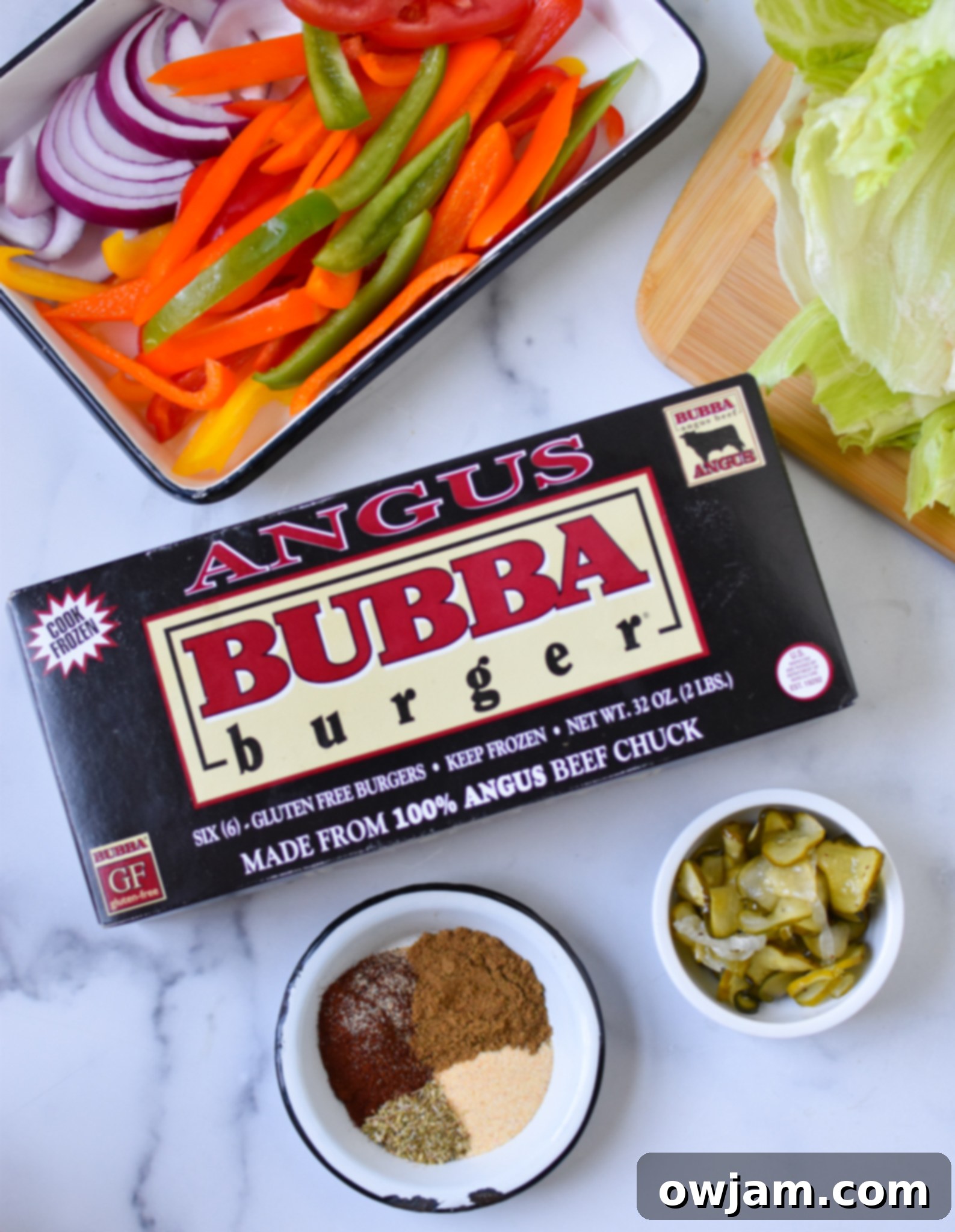 Close-up of Fajita Lettuce Burger ingredients laid out on a wooden board, including BUBBA burgers, bell peppers, onions, lettuce, and seasoning.