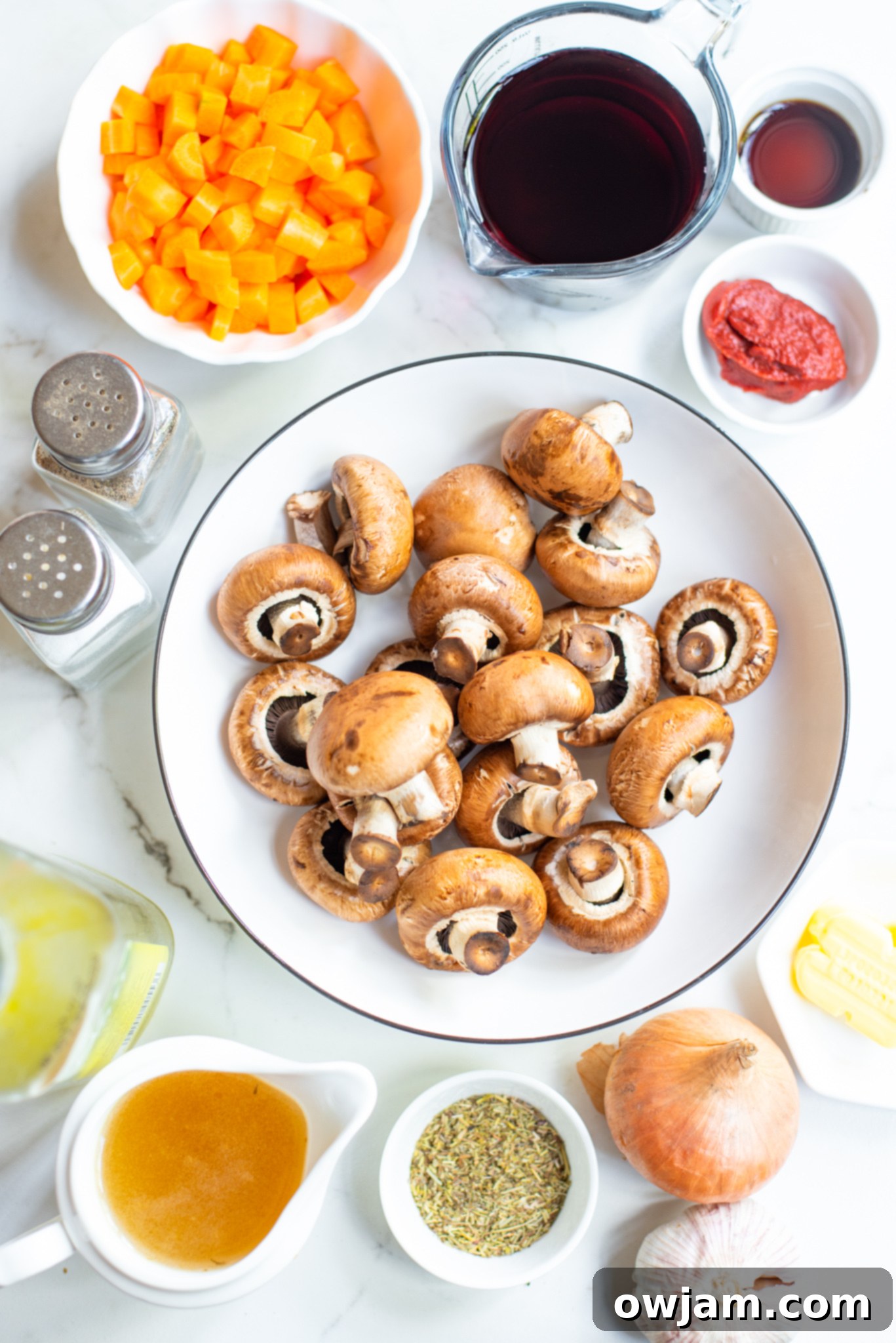 Assortment of fresh Mushroom Bourguignon ingredients including mushrooms, carrots, onions, garlic, and herbs.