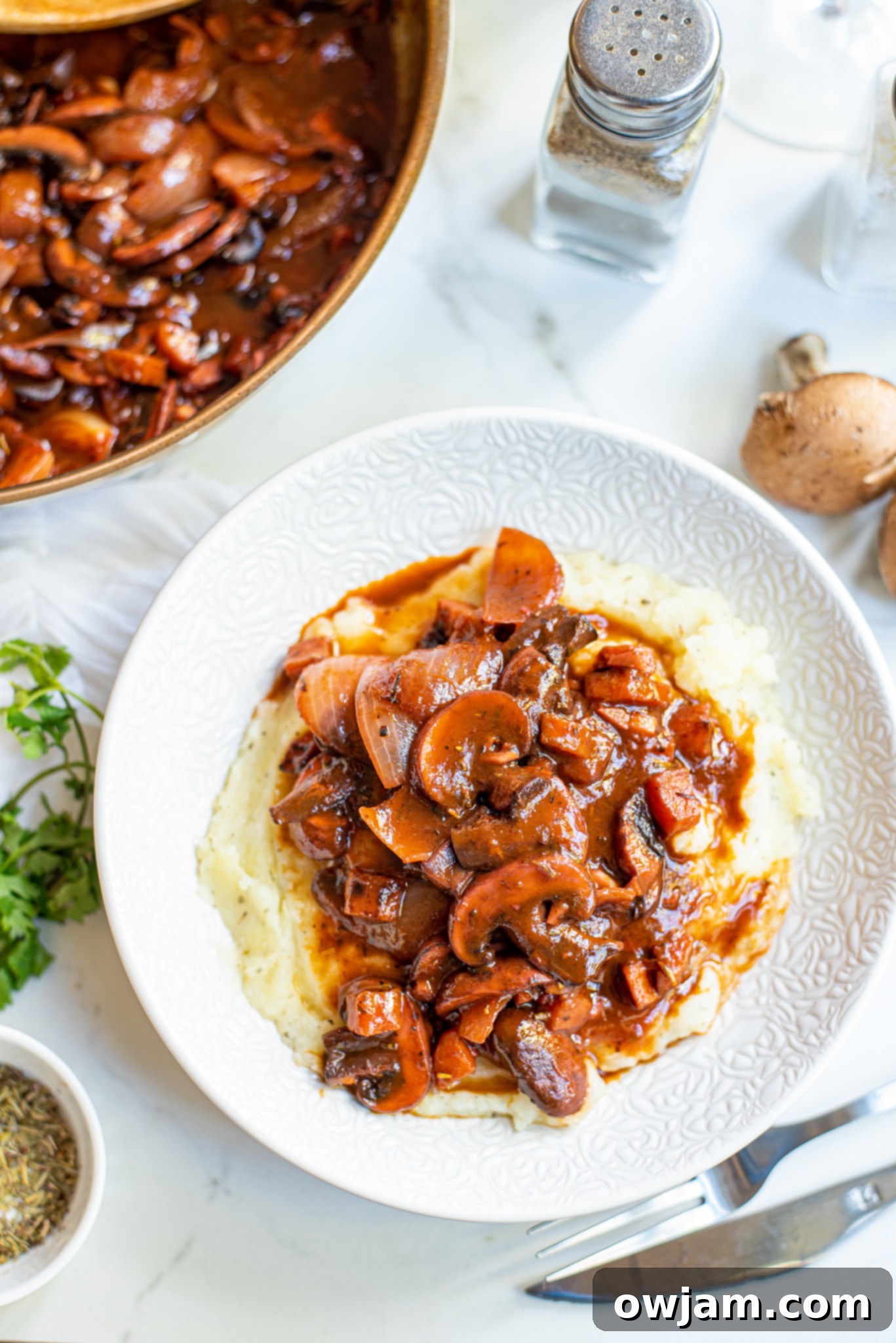 Serving of Mushroom Bourguignon on a white plate with fresh herbs.