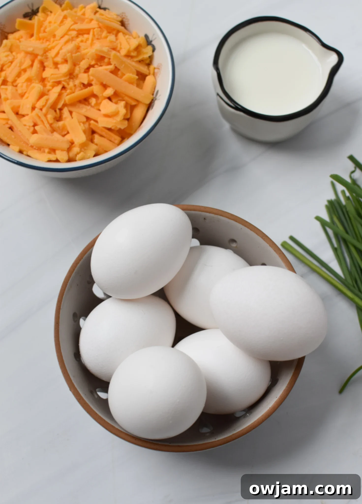 Close-up of fresh ingredients for Chaffles Recipe, including eggs, shredded cheese, and chives.