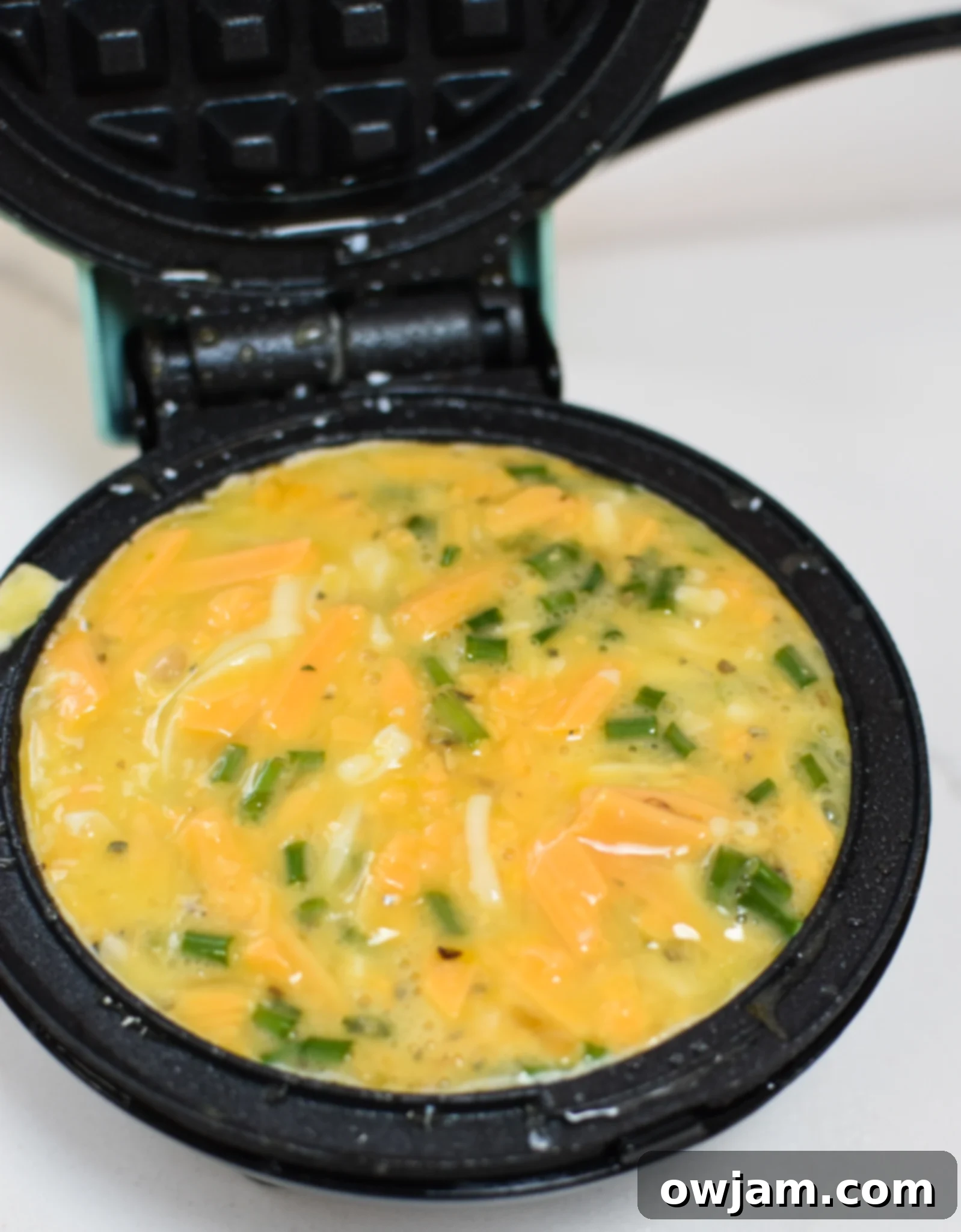 Chaffles Recipe batter being poured into a hot waffle maker, cooking to a golden crisp.