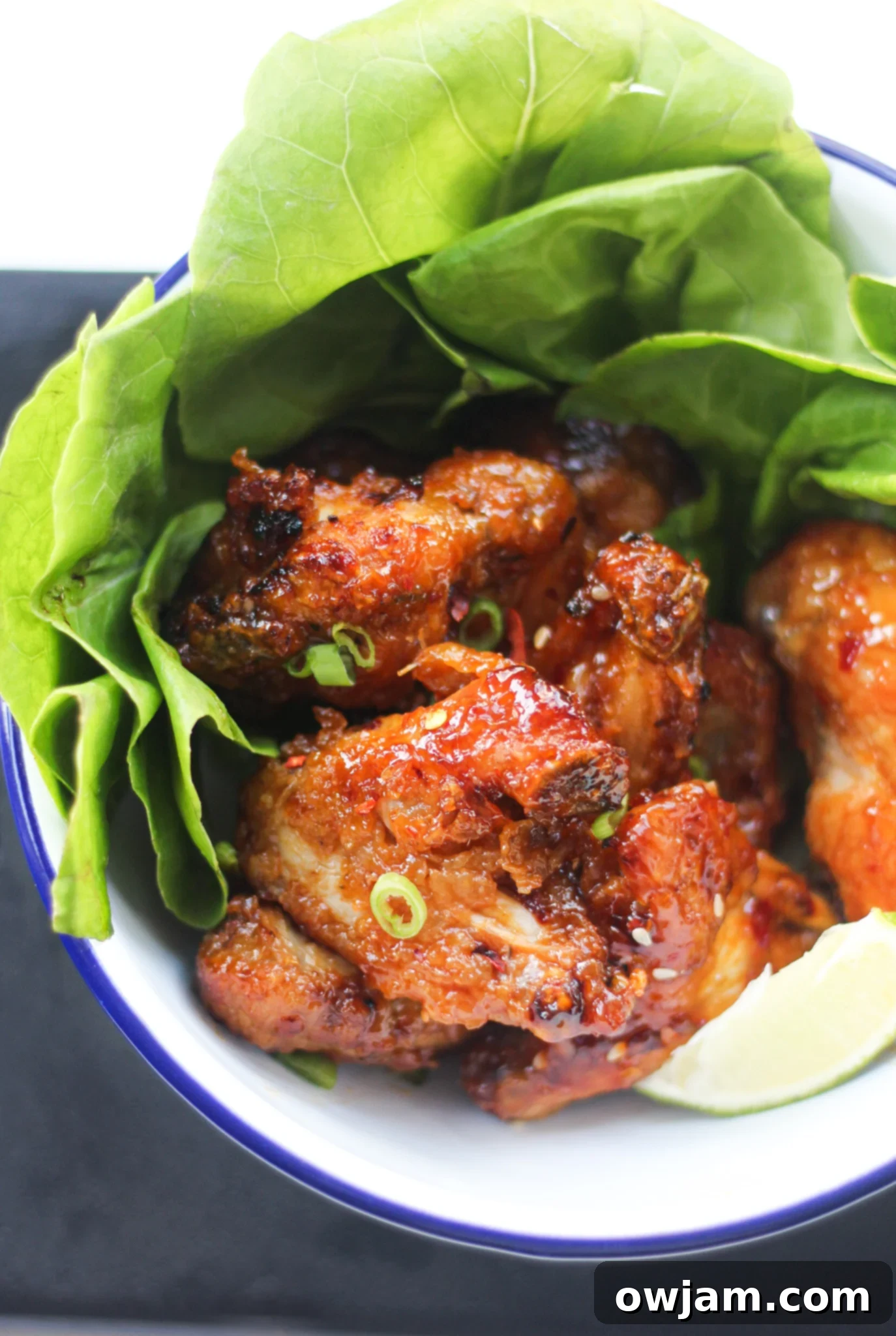 A serving of crispy Air Fryer Chicken Wings, beautifully garnished with fresh green onions and sesame seeds on a white plate.