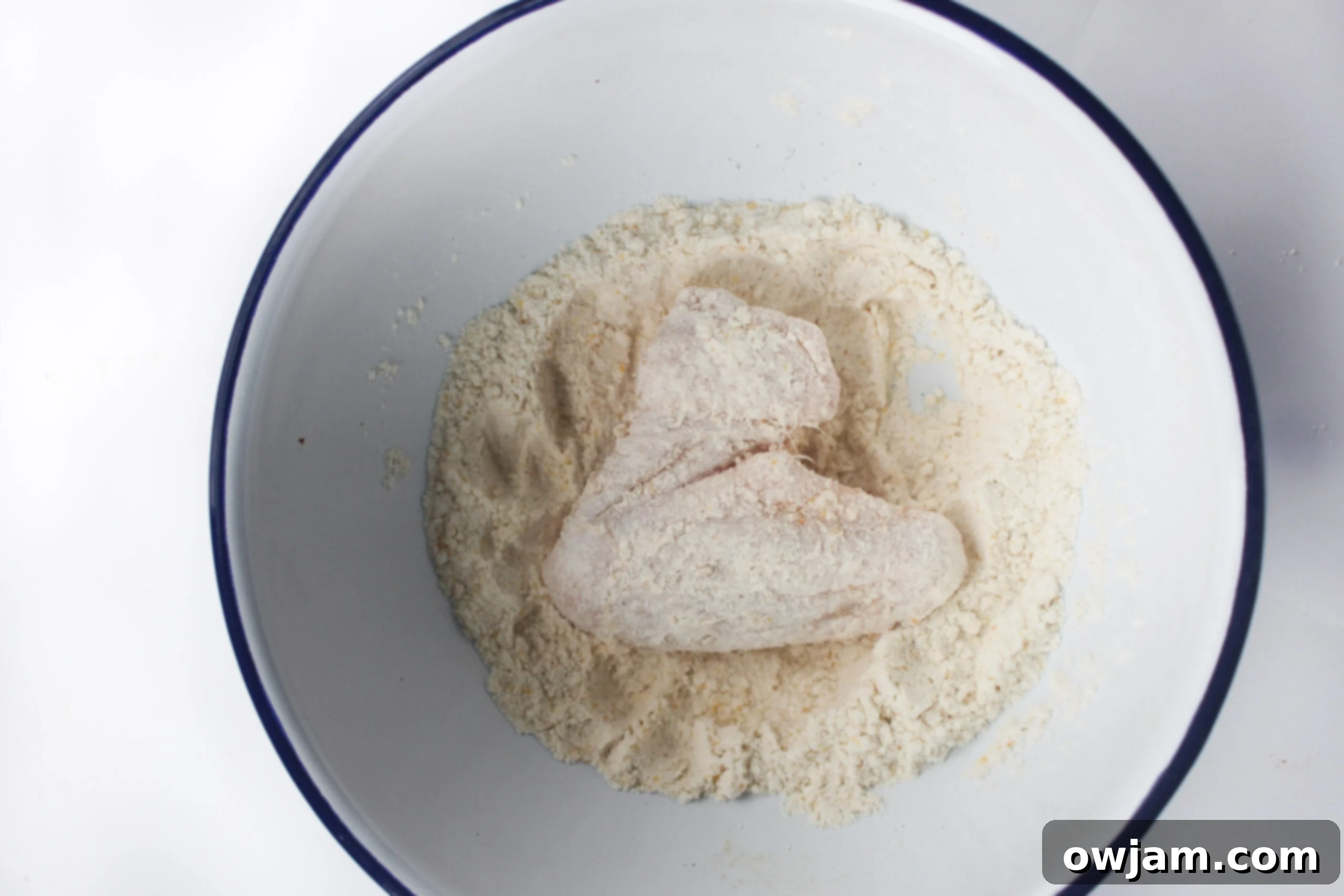 Flour-dusted chicken wings neatly arranged in an air fryer basket, ready to be cooked to perfection.