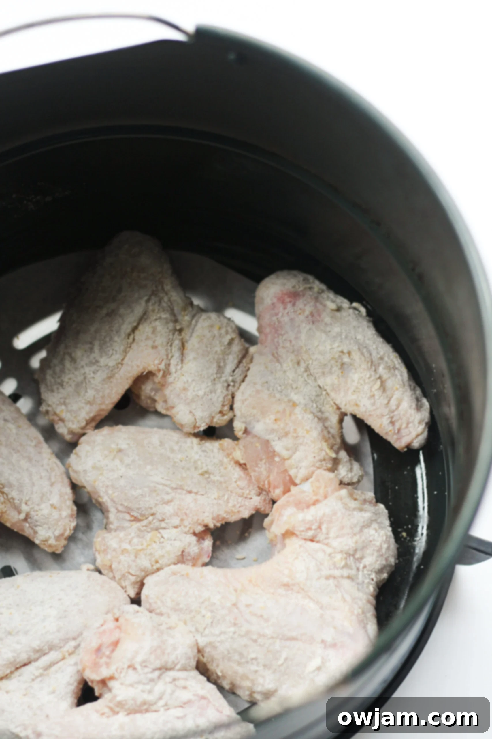 Crispy Air Fryer Chicken Wings cooking in an air fryer basket, showcasing their golden-brown and tempting texture.