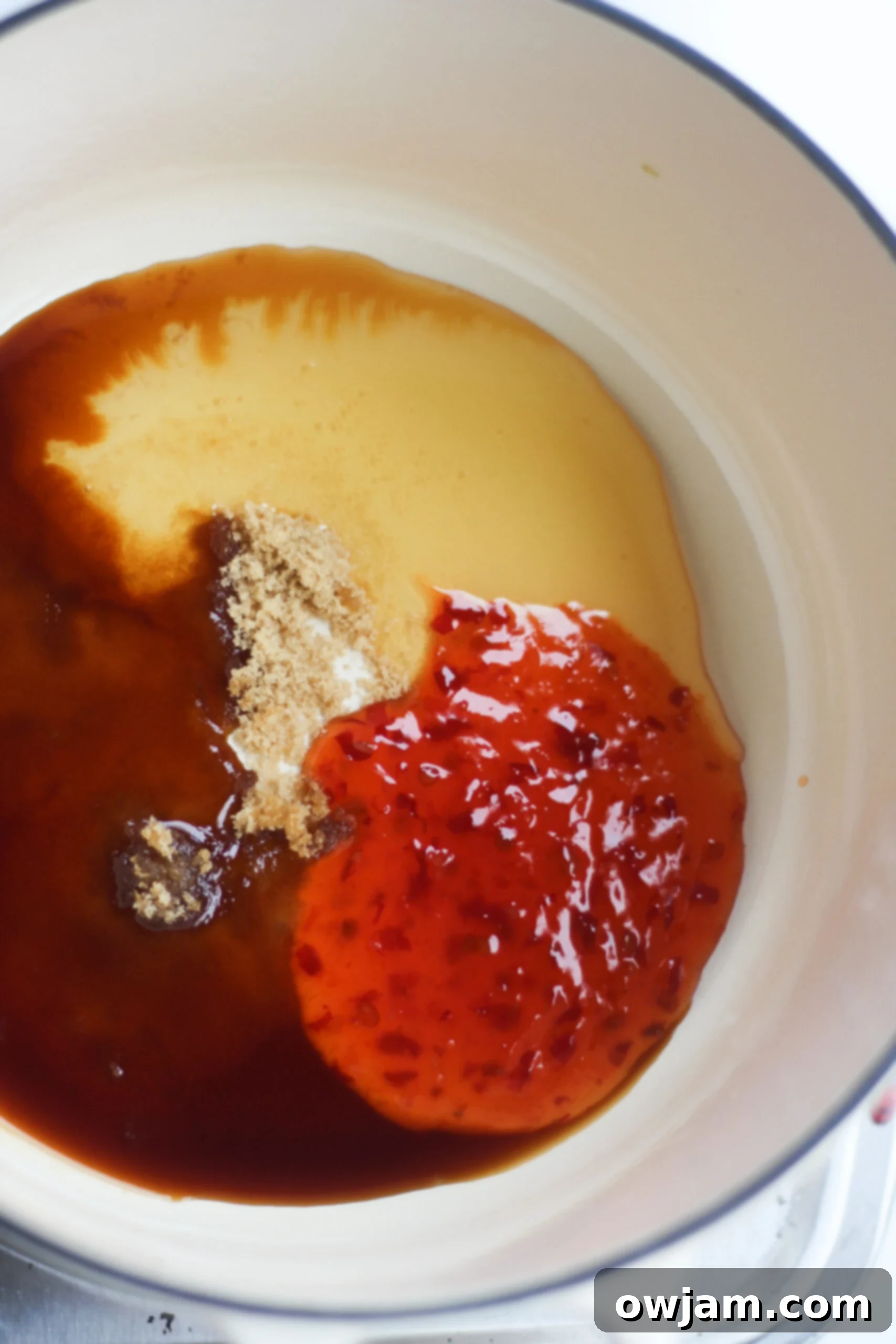 Close-up of the sweet and tangy sauce simmering gently in a skillet, showcasing its glossy texture before coating the air fryer chicken wings.