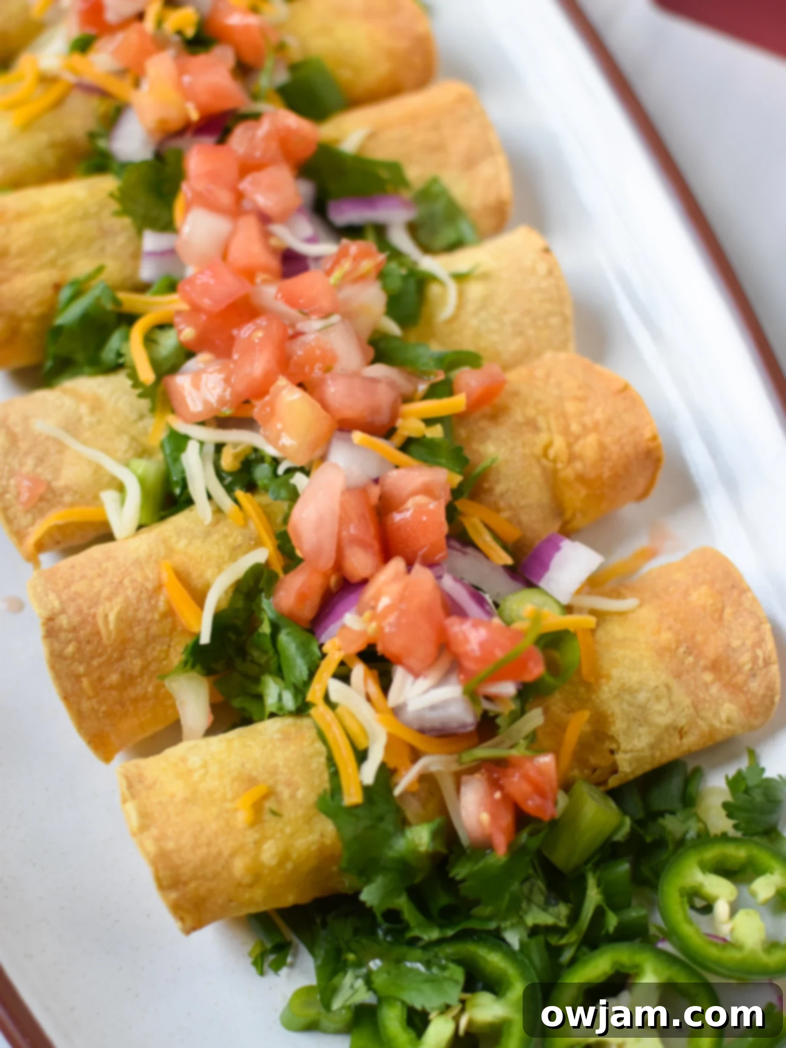 Air Fryer Pork Taquitos with pico de gallo, cilantro, and red onion. Golden brown and perfectly crispy.