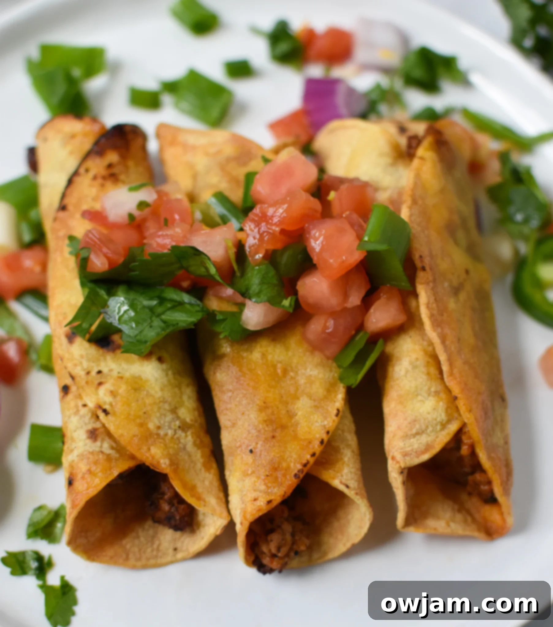 Air Fryer Pork Taquitos neatly arranged on a white plate, ready to be served.