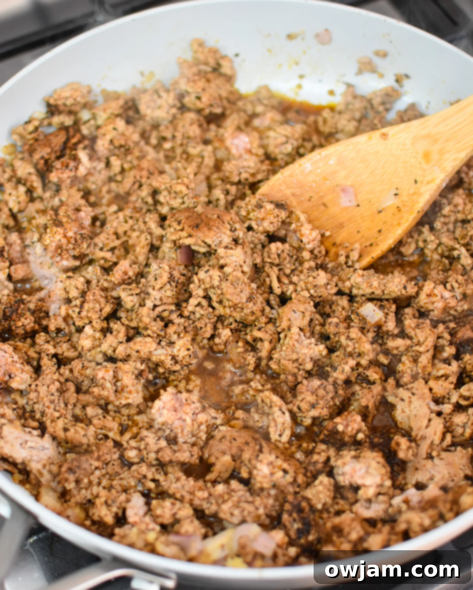Ground pork cooking in a skillet with onions and spices, forming the taquito filling.