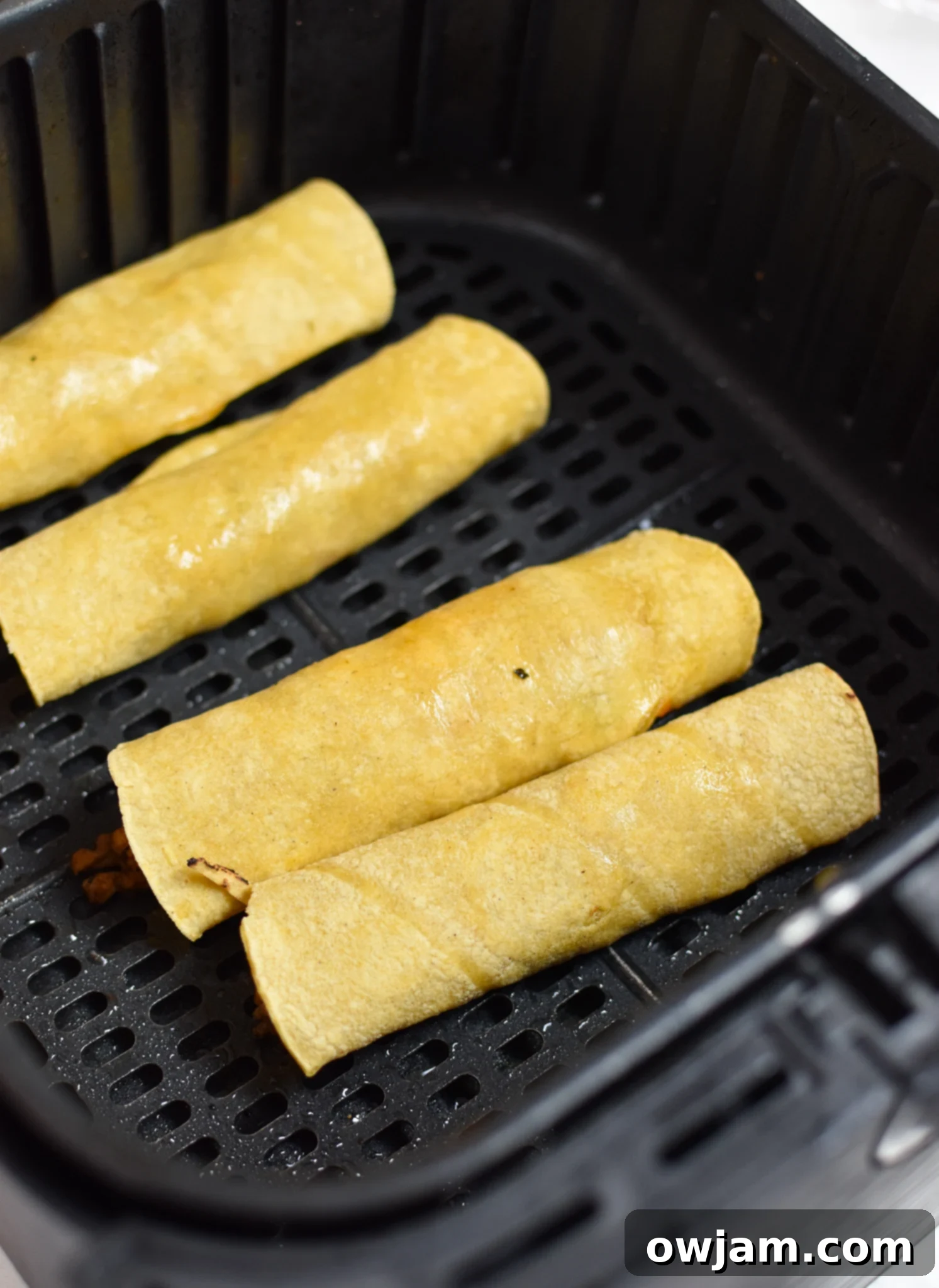 Air Fryer Pork Taquitos arranged neatly in the basket of an air fryer, ready for cooking.
