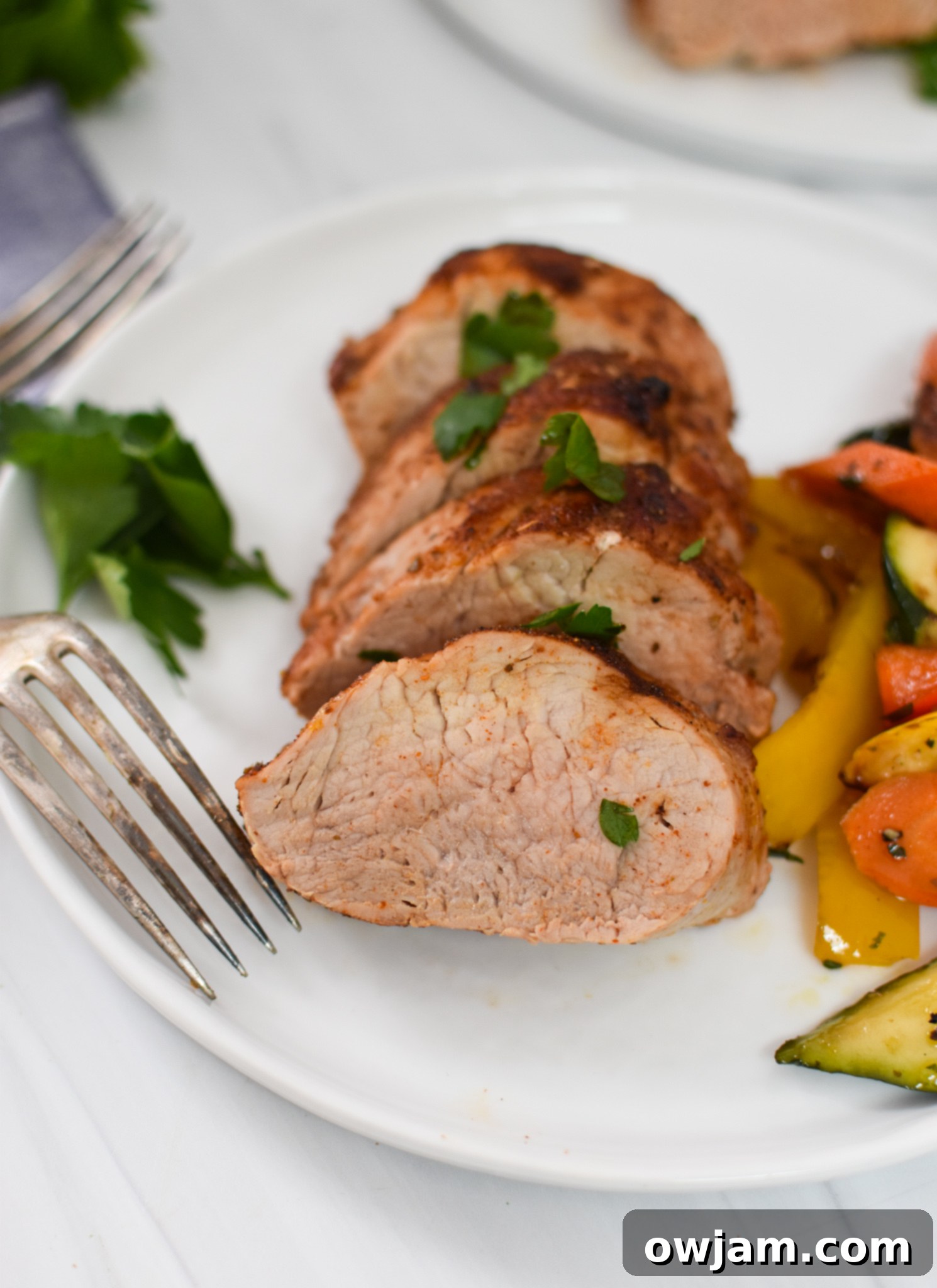 Air Fryer Pork Tenderloin on a white plate with a fork, ready to be enjoyed.