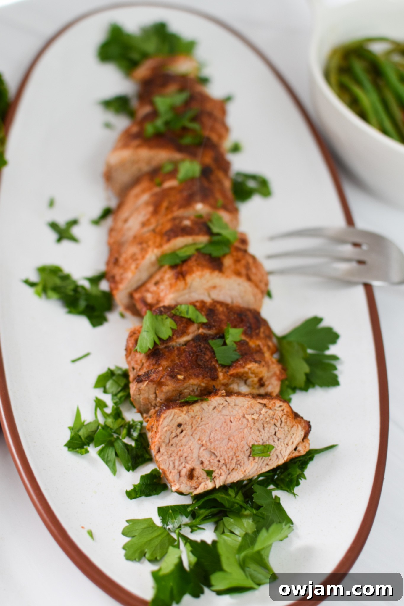 Sliced Air Fryer Pork Tenderloin on a white platter, ready to be served.