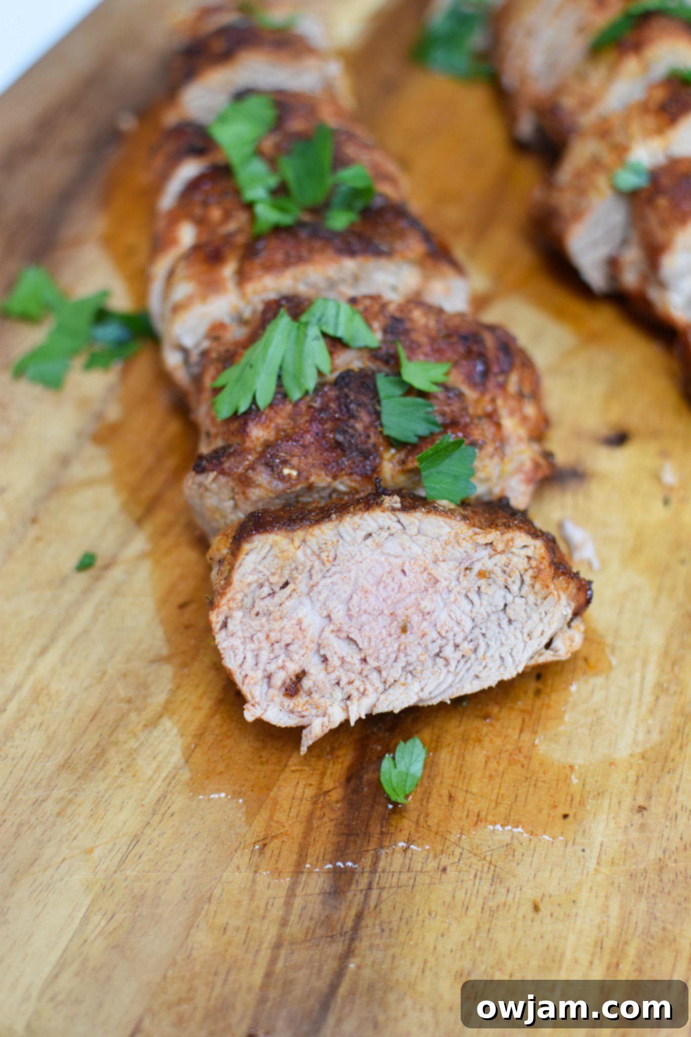 Air Fryer Pork Tenderloin sliced on a cutting board, garnished and ready.
