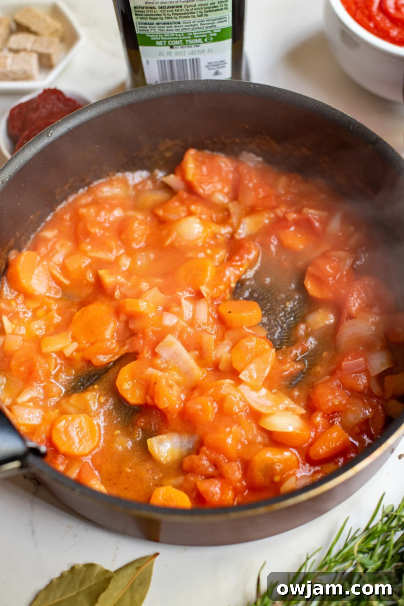 Rich tomato and vegetable sauce simmering in a skillet for braised lamb shanks.