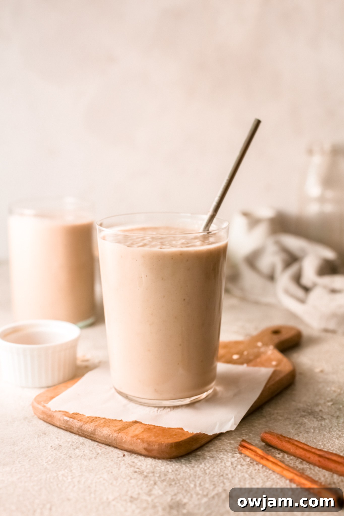 A tall glass of creamy oat smoothie, garnished with a sprinkle of cinnamon, ready to be enjoyed.