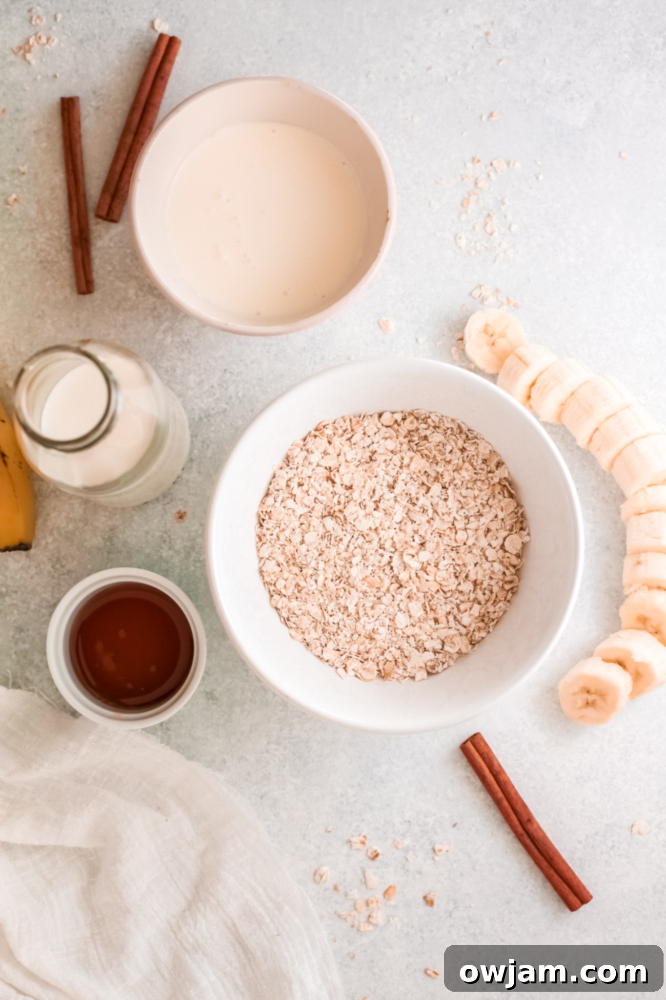 Close-up of fresh ingredients for Oat Smoothie Recipe, including bananas, oats, Greek yogurt, milk, cinnamon, and maple syrup.