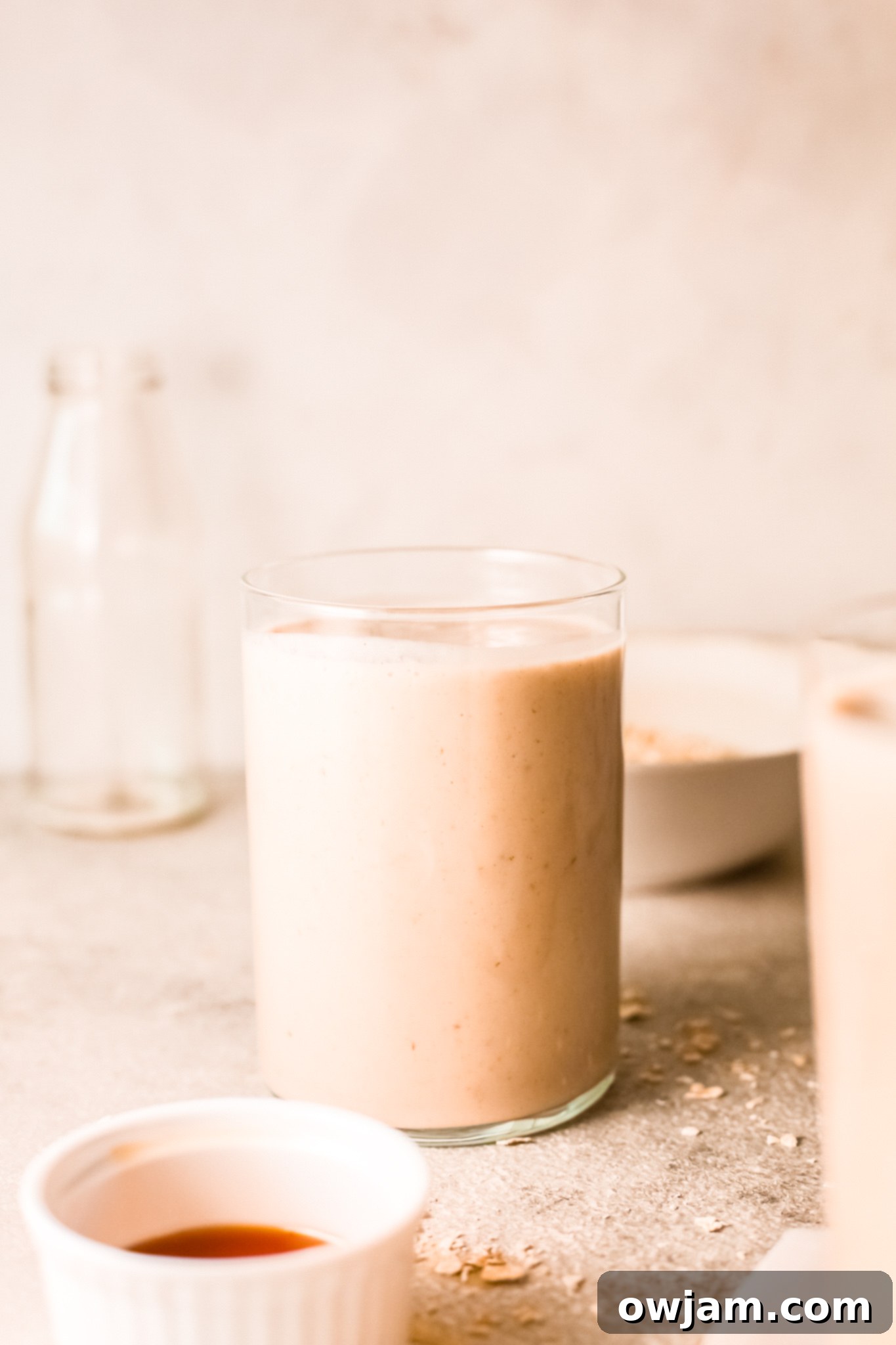 A refreshing oat smoothie served in a clear glass with a straw, ready to be enjoyed.