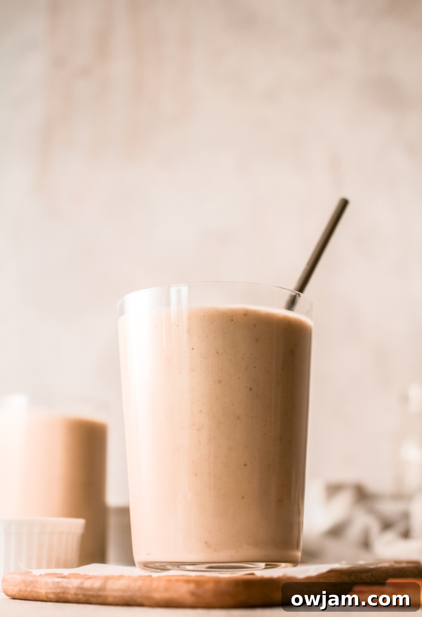 A refreshing and thick oat smoothie in a glass with a straw, ready to drink.