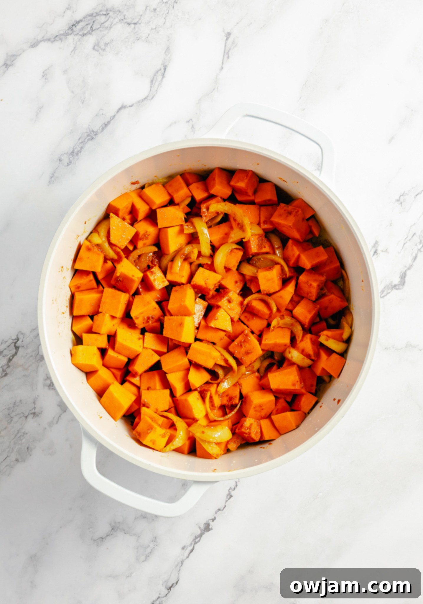 Close-up of diced pumpkin coated in spices in a large pot, cooking for the Pumpkin Curry Recipe.