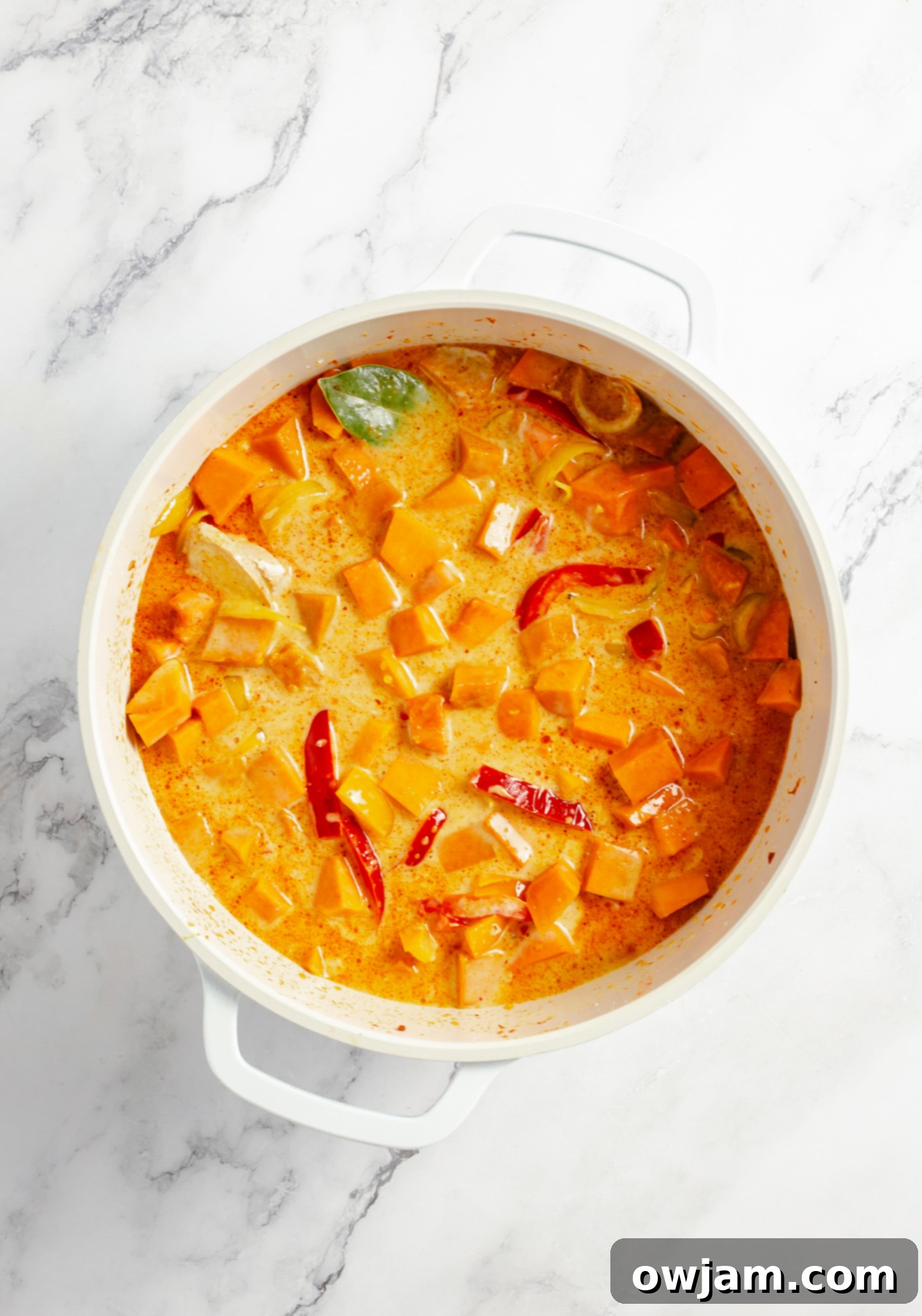 Pumpkin curry simmering in a pot, with broth and coconut milk just added, to soften the pumpkin.