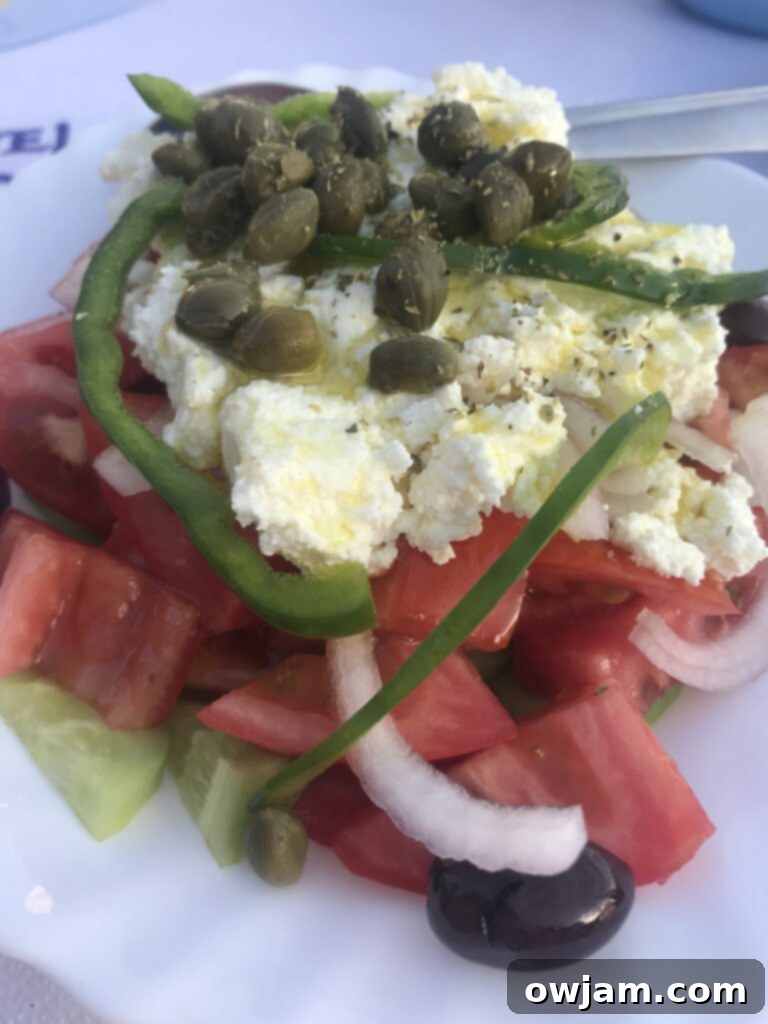 Vibrant Mediterranean Quinoa Salad 3 A traditional Greek salad served in Naxos, Greece, featuring large slices of tomato, cucumber, onion, feta cheese, olives, and capers, on a rustic table.