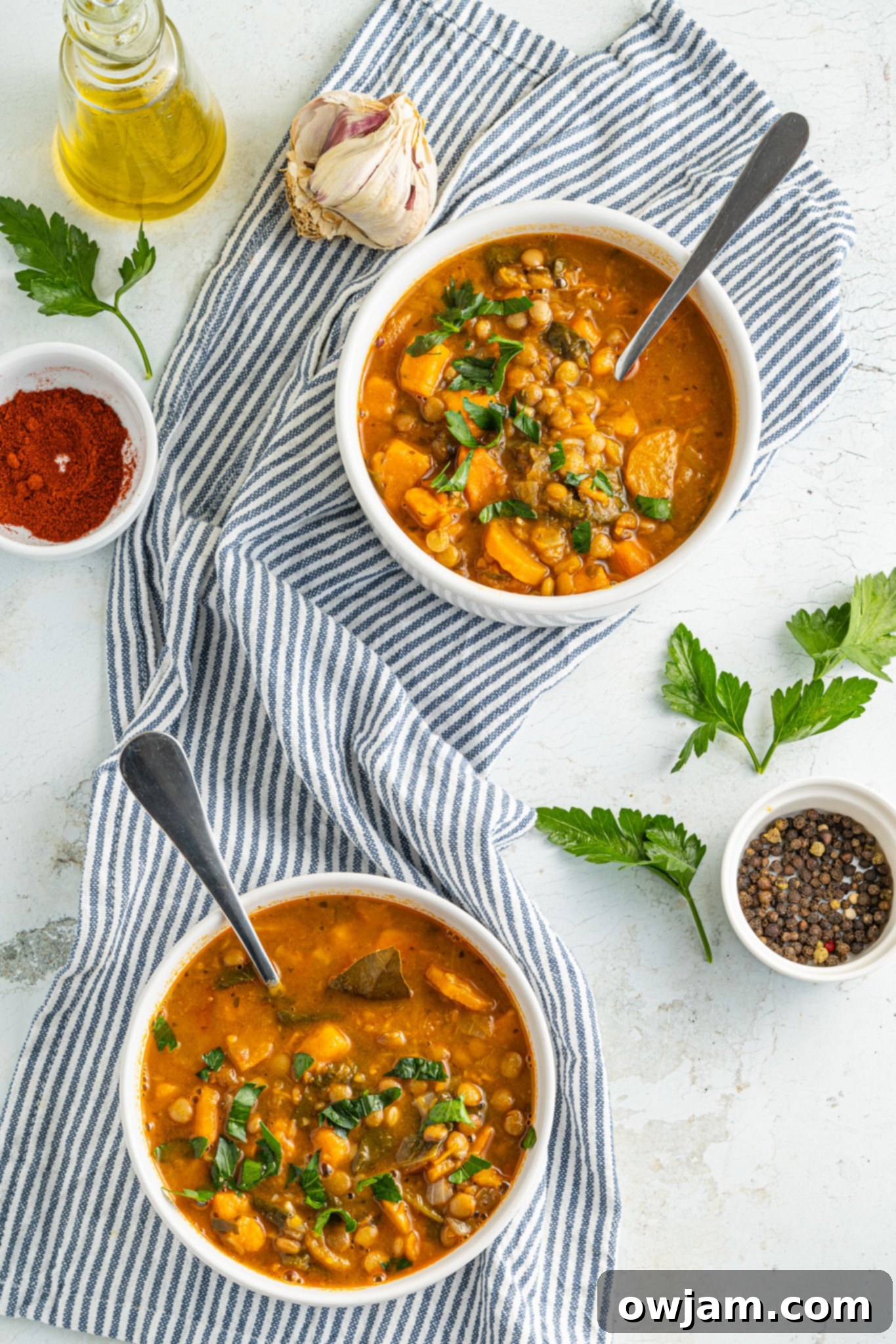 Three bowls of Sweet Potato Lentil Soup, garnished with fresh herbs and a lemon wedge, invitingly presented.