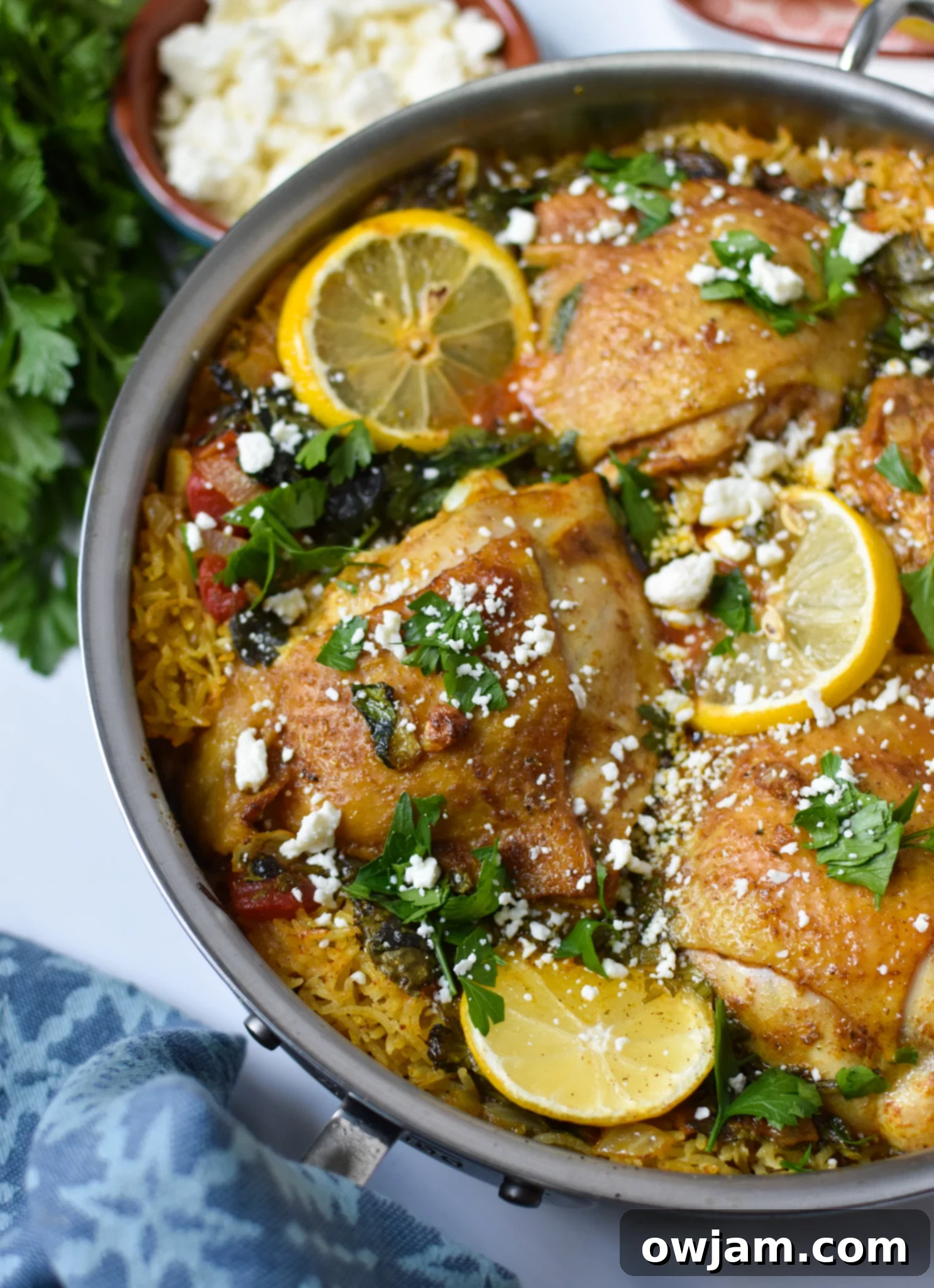 One Pot Mediterranean Chicken and Rice in a pot, garnished with fresh herbs and lemon.