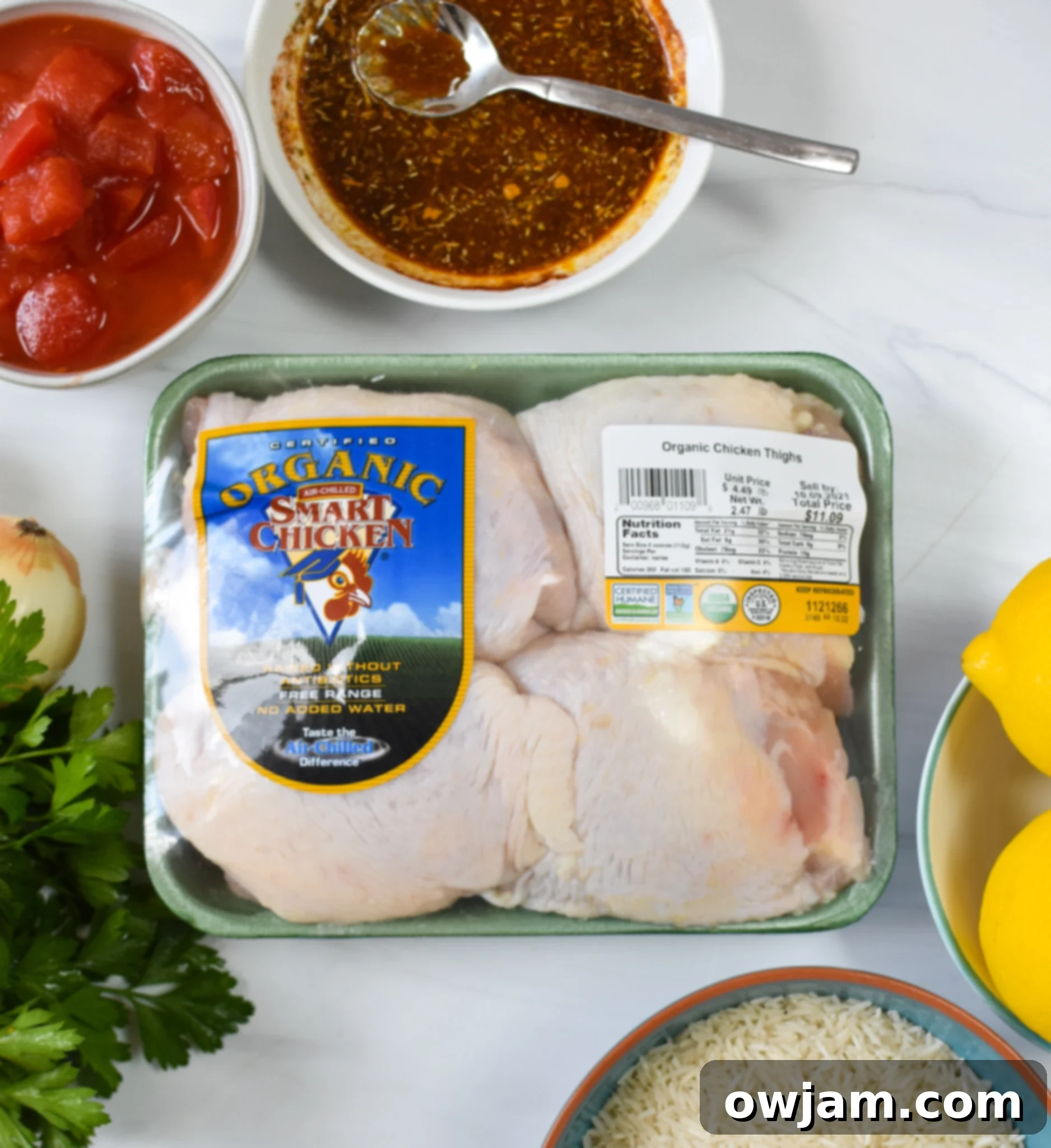 Collection of fresh ingredients for One Pot Mediterranean Chicken and Rice, including chicken thighs, rice, lemons, and various spices.