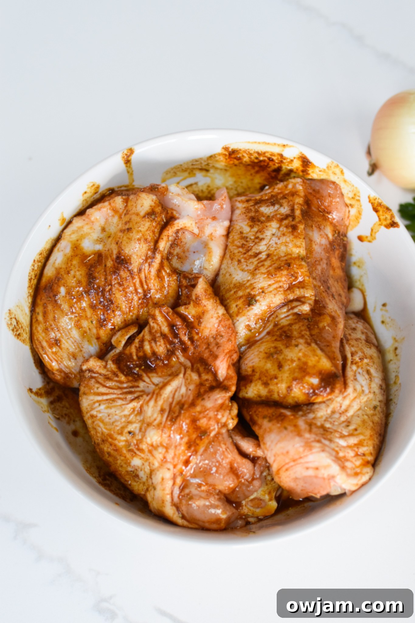 Marinated chicken thighs in a bowl for One Pot Mediterranean Chicken and Rice.