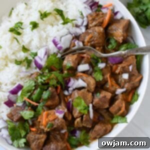 Slow Cooker Beef Curry served over rice with cilantro and red onion garnish.